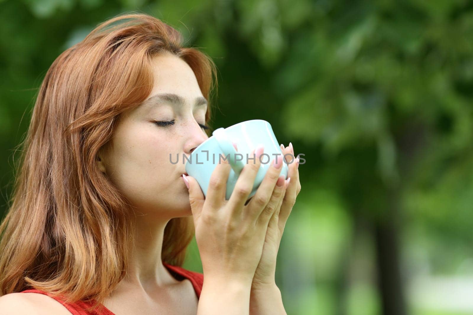 Woman drinking coffee from mug in a park