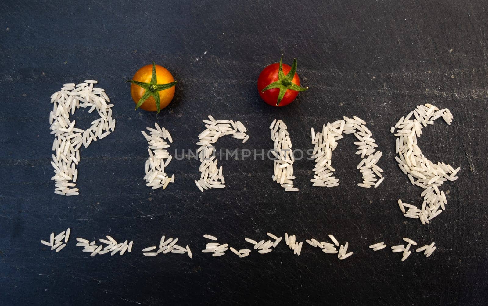 Turkish word pirinç written by white rice grains on a black slate board
