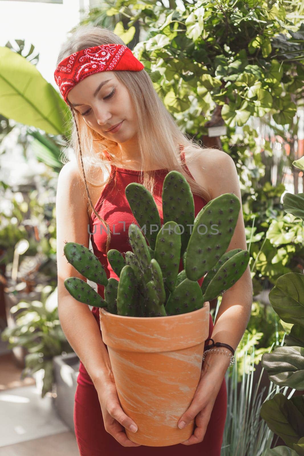 Woman holding big pot with cactus in garden