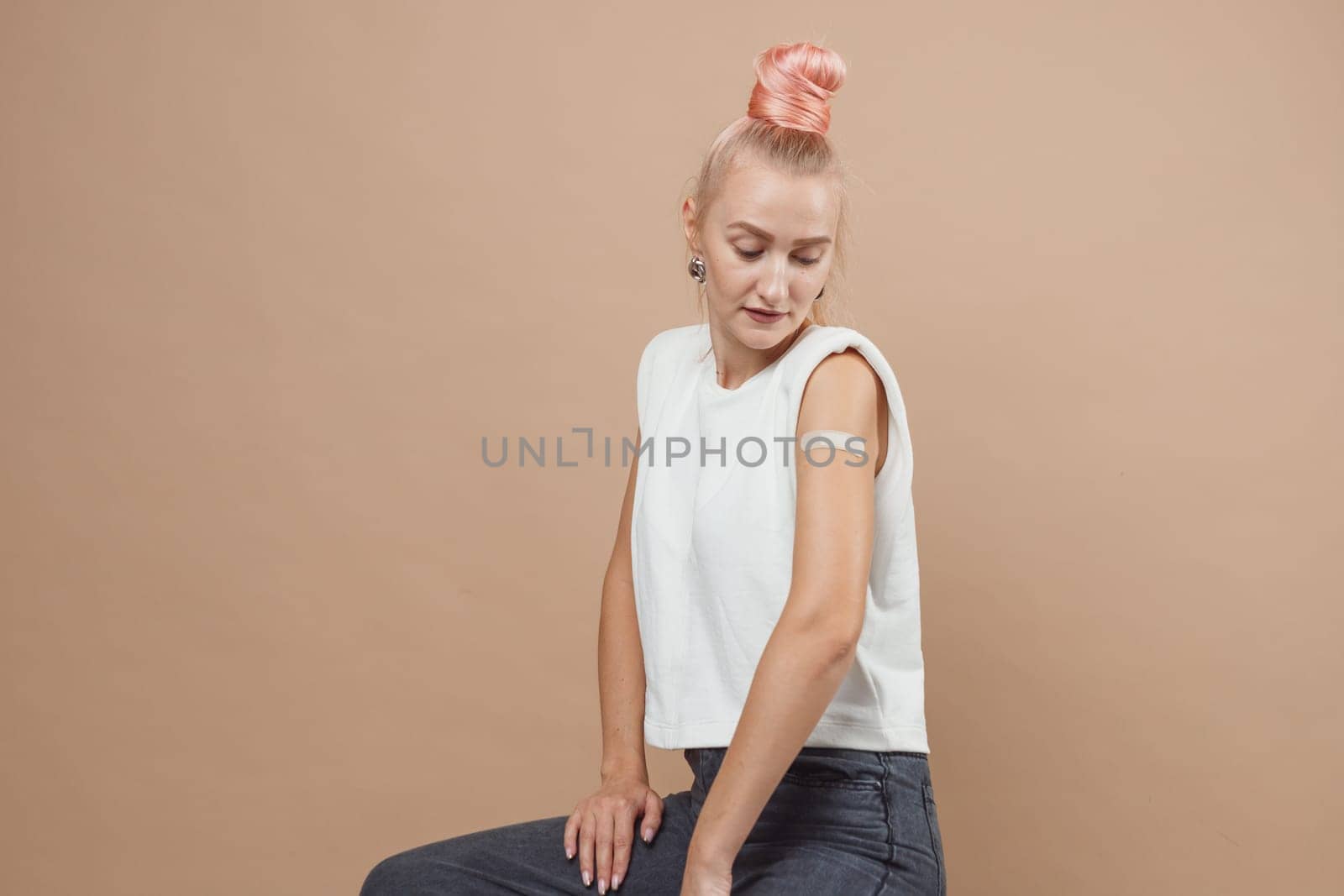 Young hipster woman with band aid after coronavirus Covid-19 vaccine injection. Covid vaccination concept, plain color background