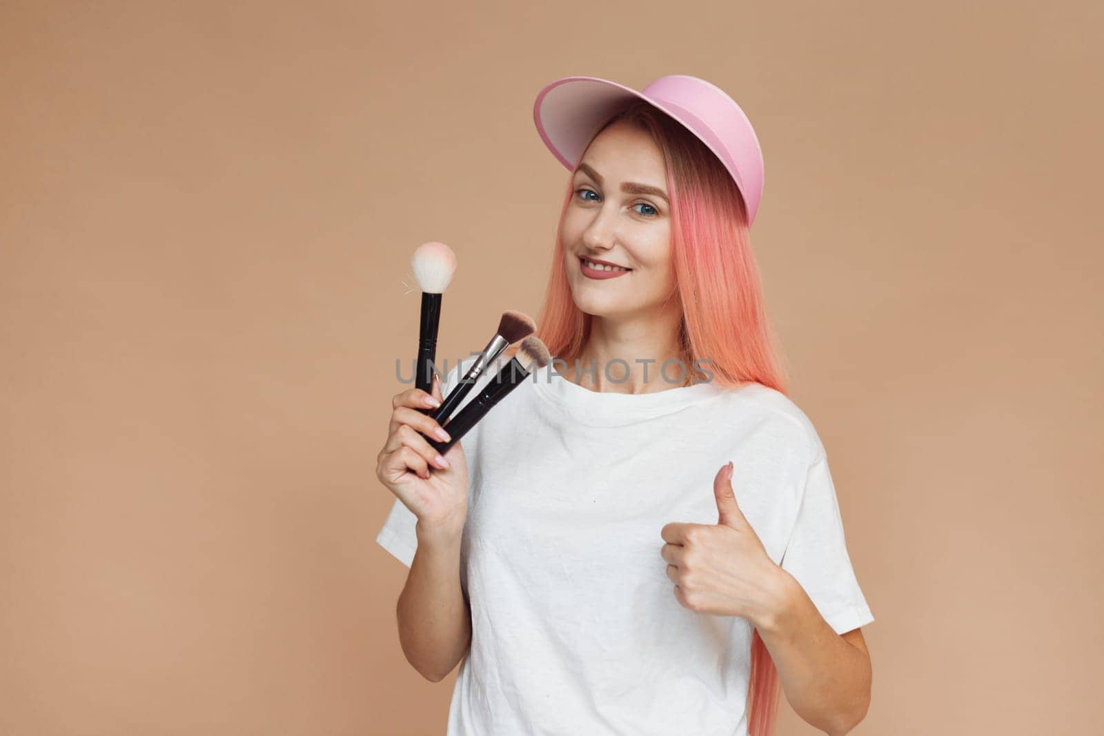 portrait of make up artist woman with makeup brushes near face. beauty concept. Isolated on beige background