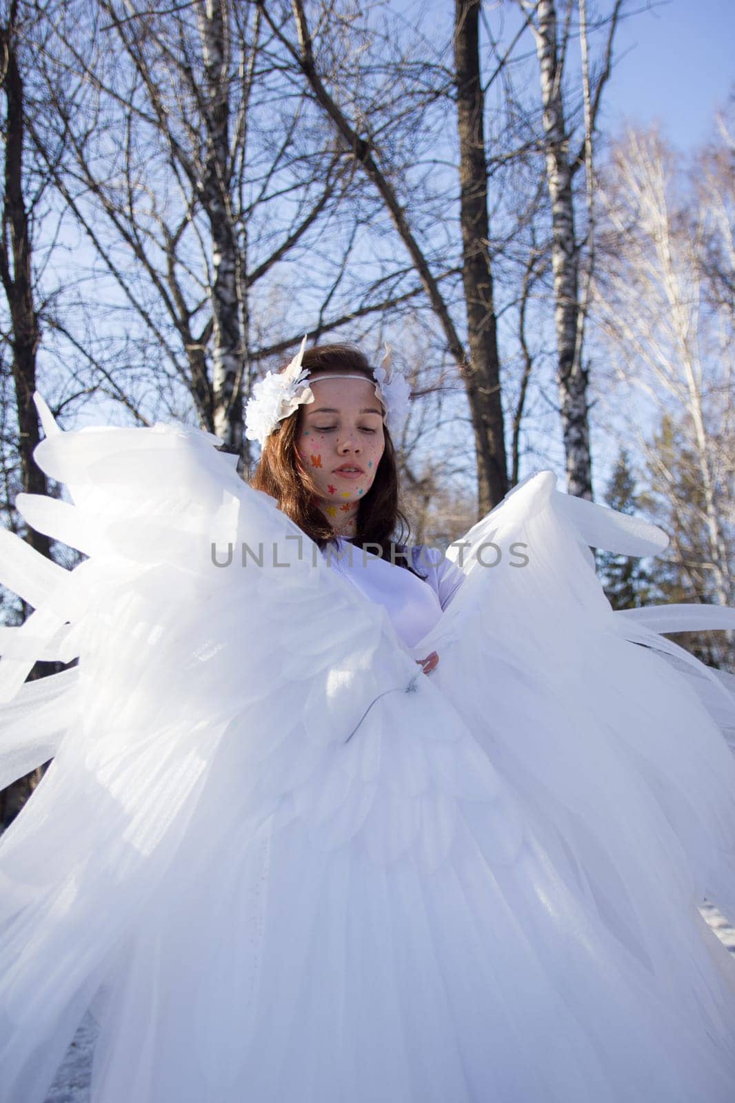 A beautiful angel by the river in winter against the blue sky.