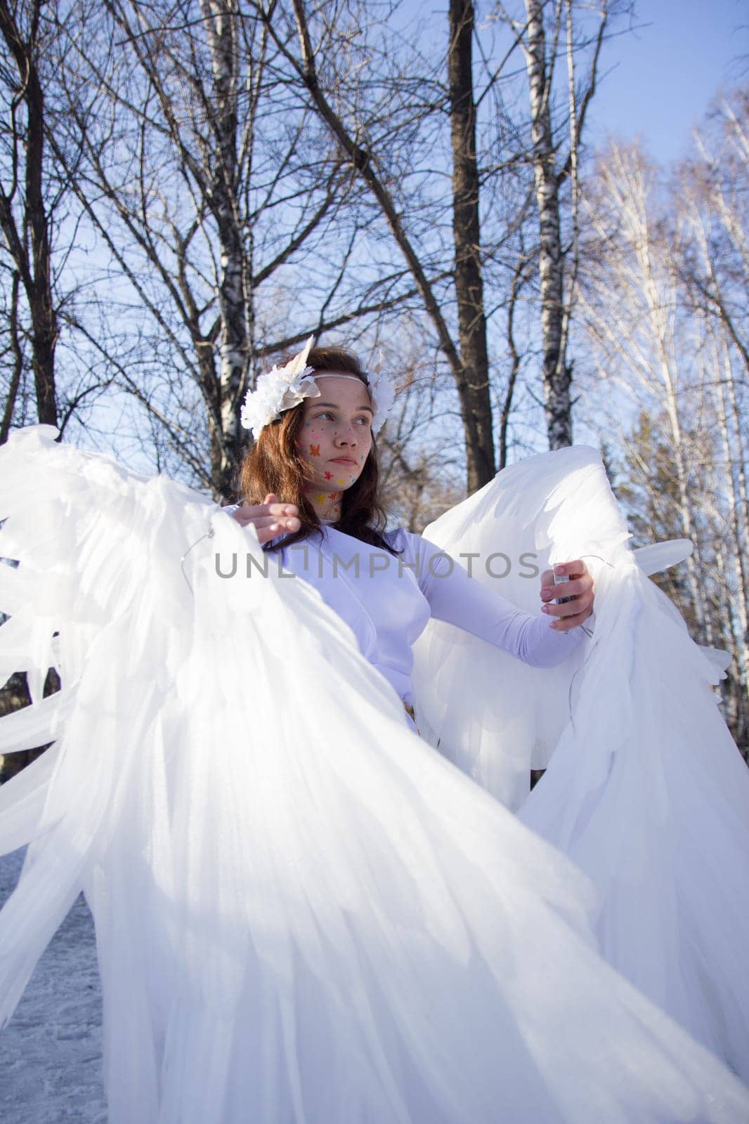 A beautiful angel by the river in winter against the blue sky.