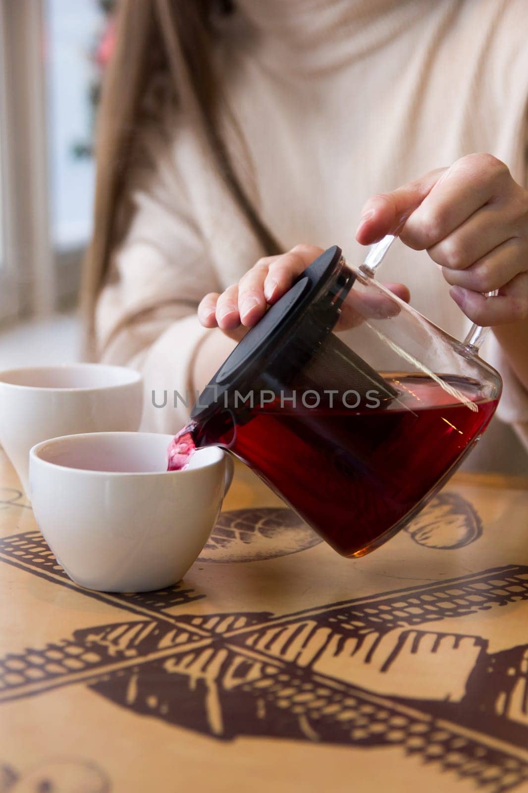 Pour the hot tea into a cup. The cup of tea on the wooden table was illuminated by the soft sunlight that penetrated the warm atmosphere