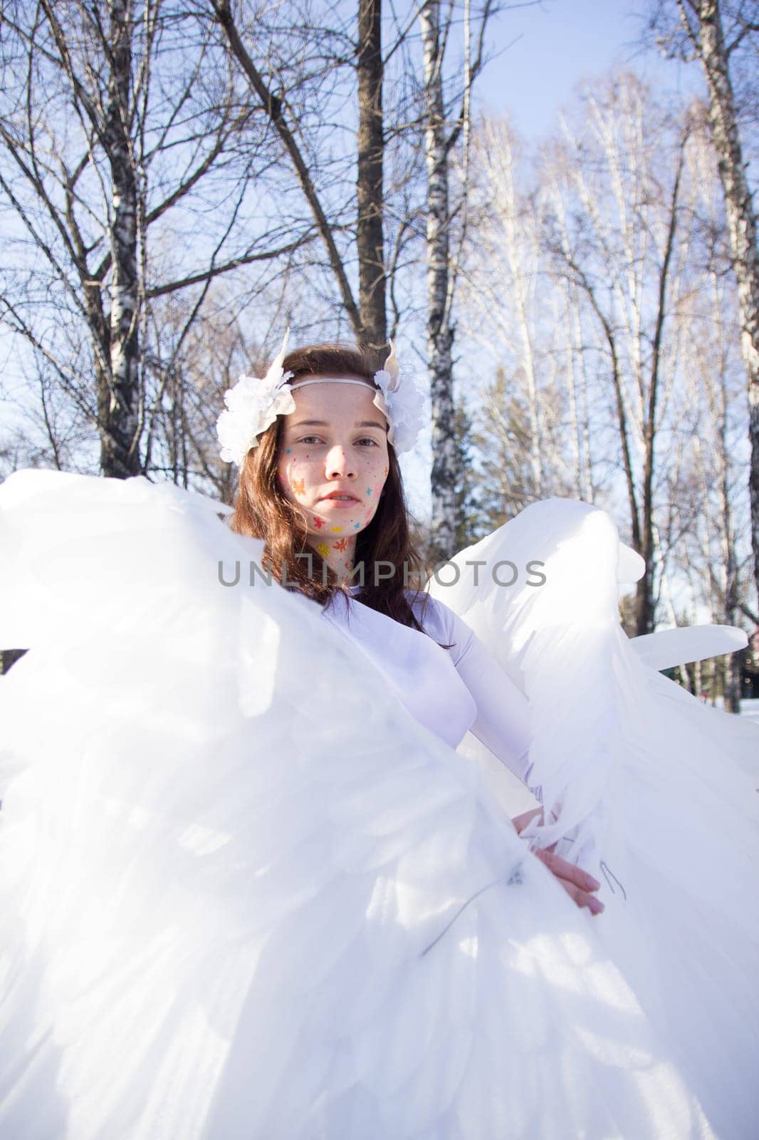 A beautiful angel by the river in winter against the blue sky.