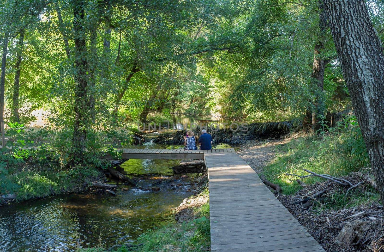 Gevora river, La Codosera, Badajoz, Extremadura, Spain. Elder couple sitting over wooden bridge