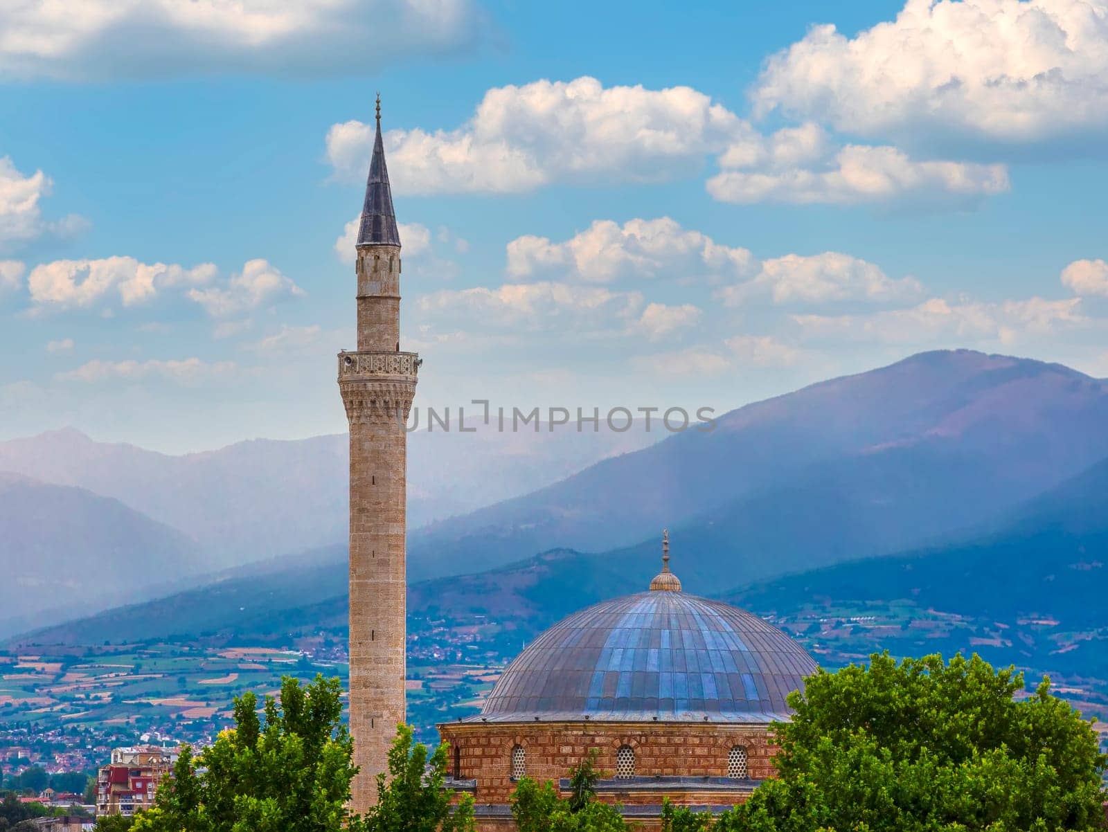 The minaret of the mosque and the trees on the background of the sky. and hills. Selective focus