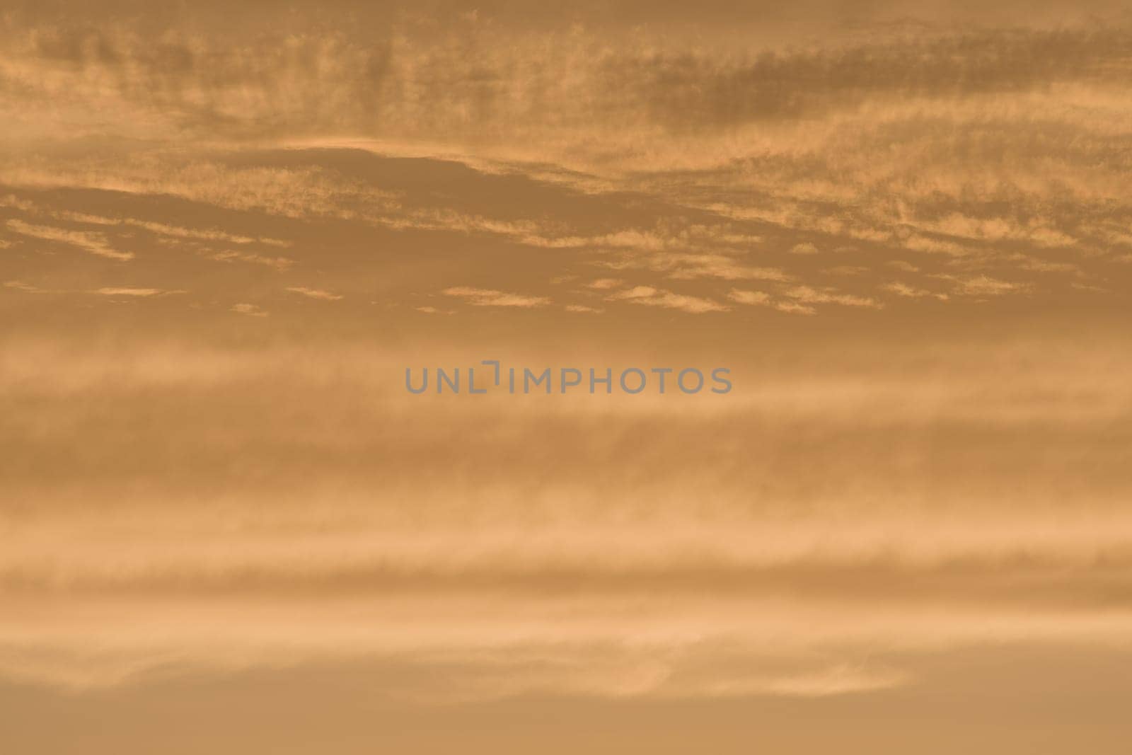 Abstract sky background of deep golden sunset clouds. Full frame color and texture, copy space possible throughout. Rich tones and varied clouds.
