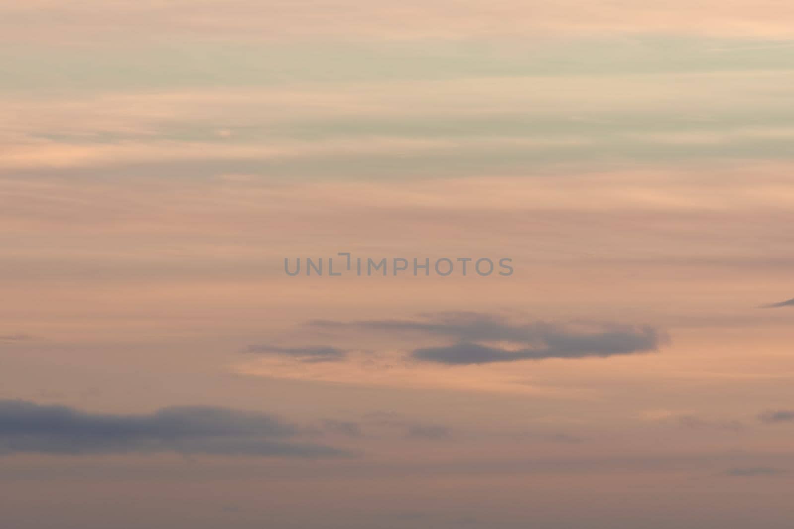 Plain pastel color themed background, made by a sky of gentle clouds at sunset. Mainly orange with some blue, very calm and wispy. Lots of copy space