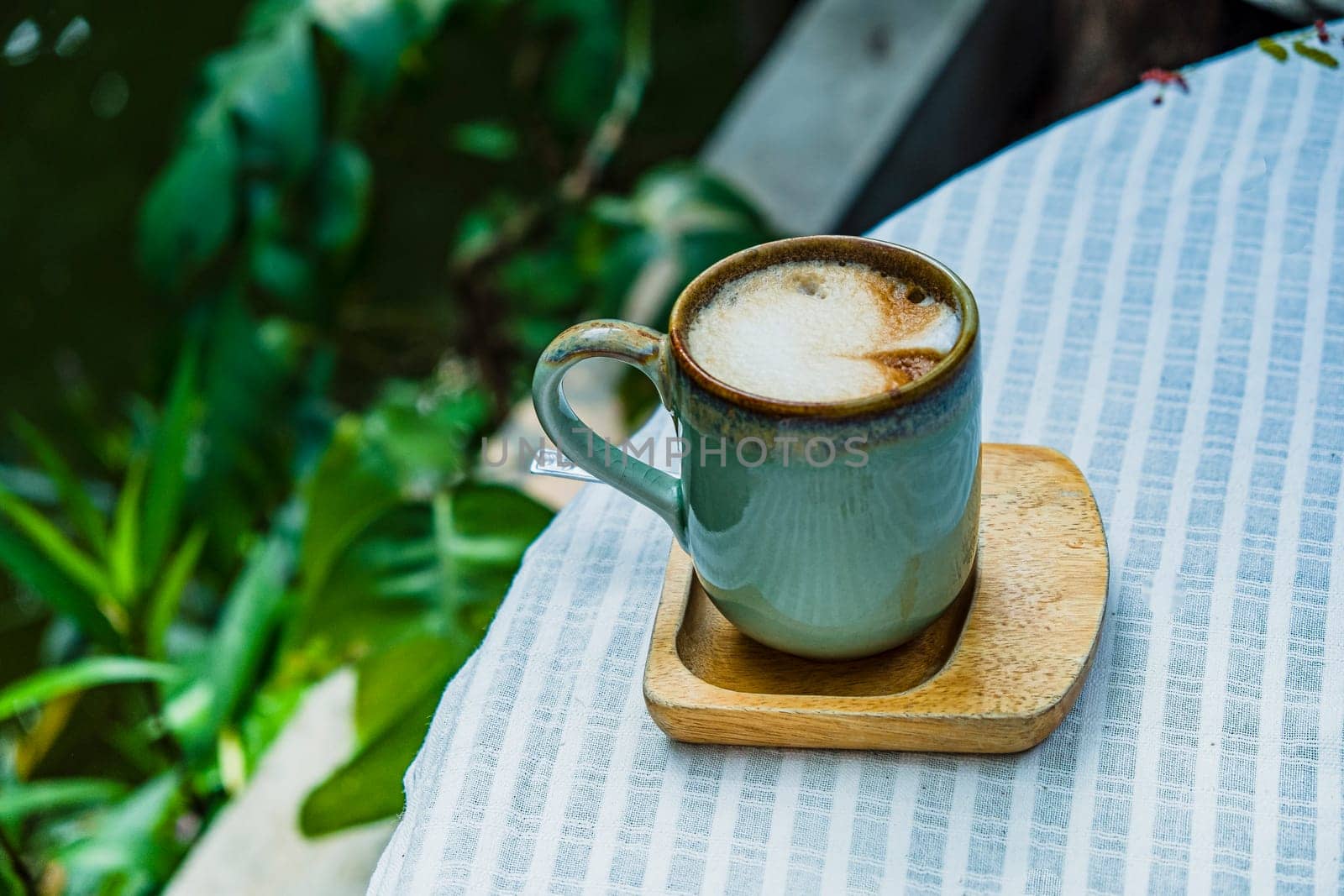 Cup of coffee latte with heart shape on old wooden background in the morning sunlight