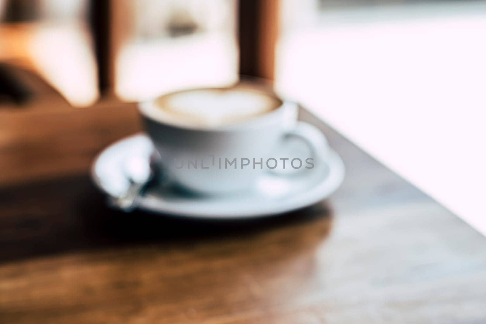 Cup of coffee latte with heart shape on old wooden background in the morning sunlight