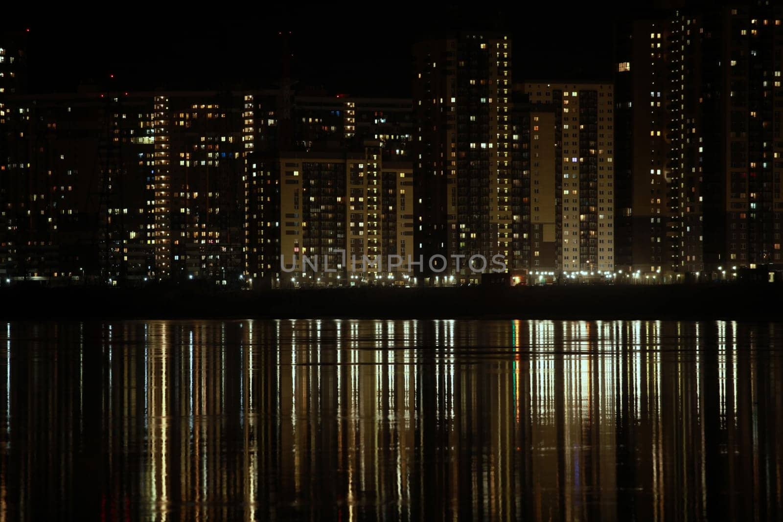 night light in the windows of skyscrapers is reflected in the river, cityscape