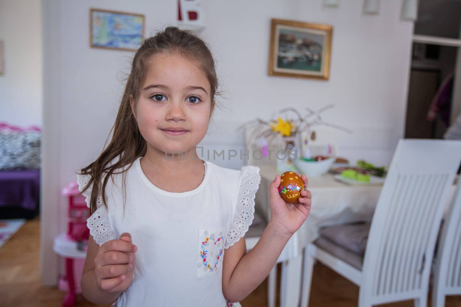 Portrait of adorable little girl with colorful Easter eggs at home, Holiday day