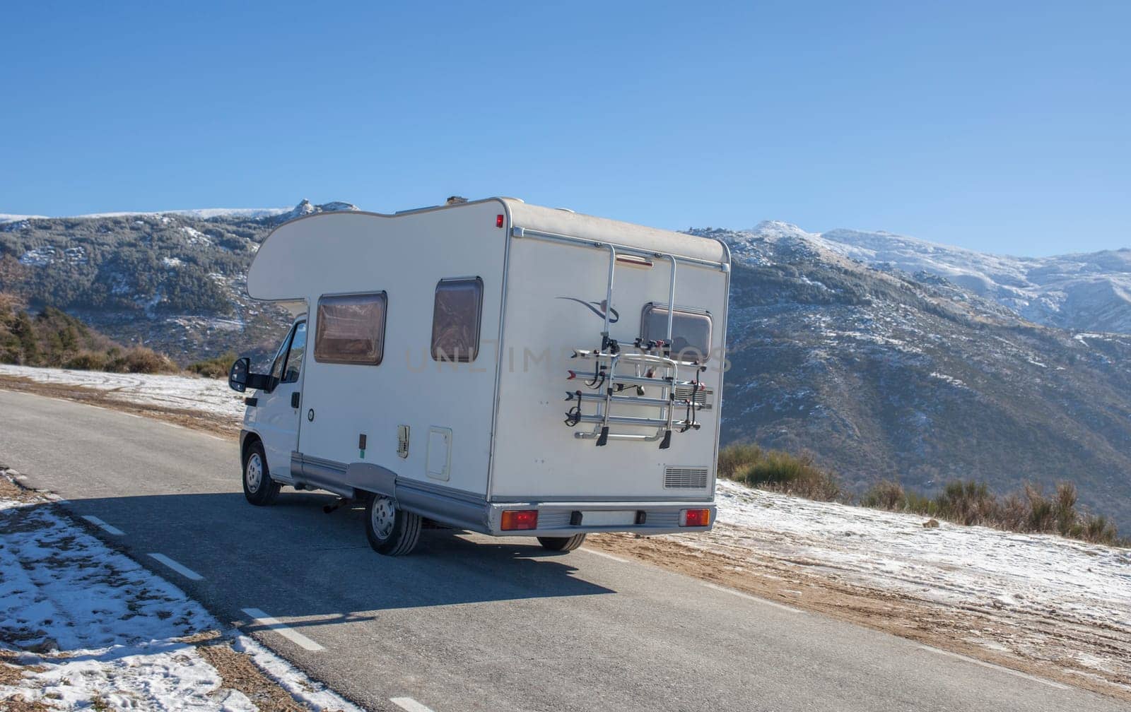 Motorhome climbing slowly by mountains pass. Rear outdoor view