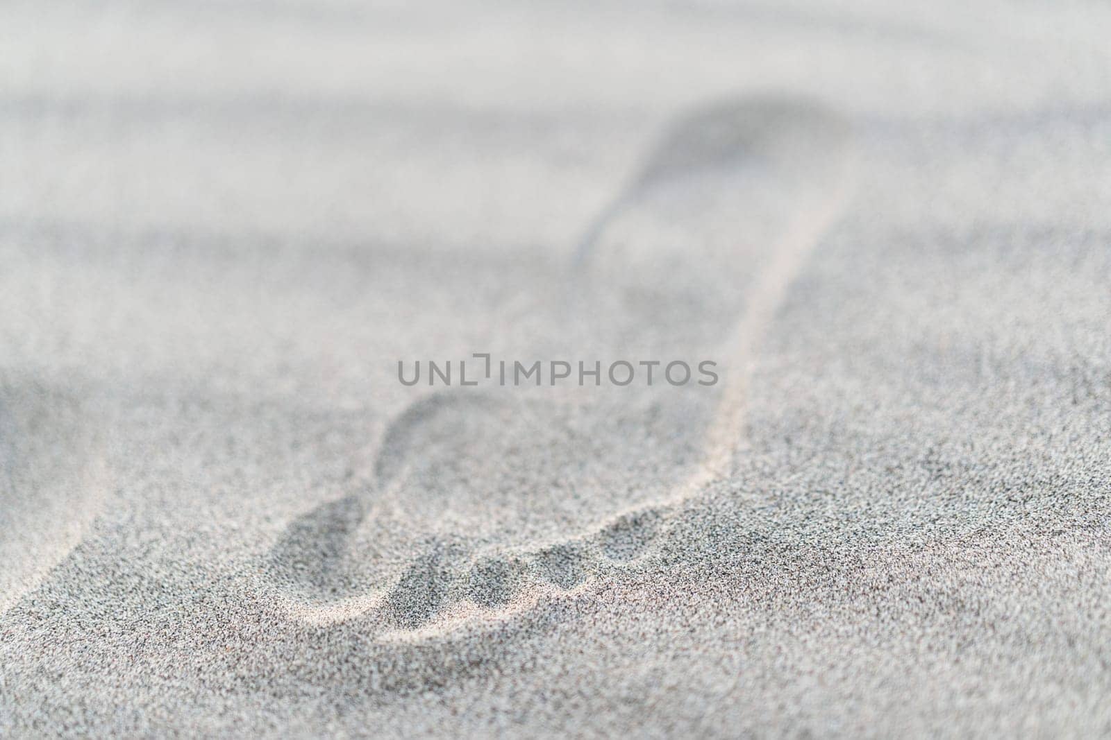 closeup top view of small child footstep imprinted in sand with shallow depth of field