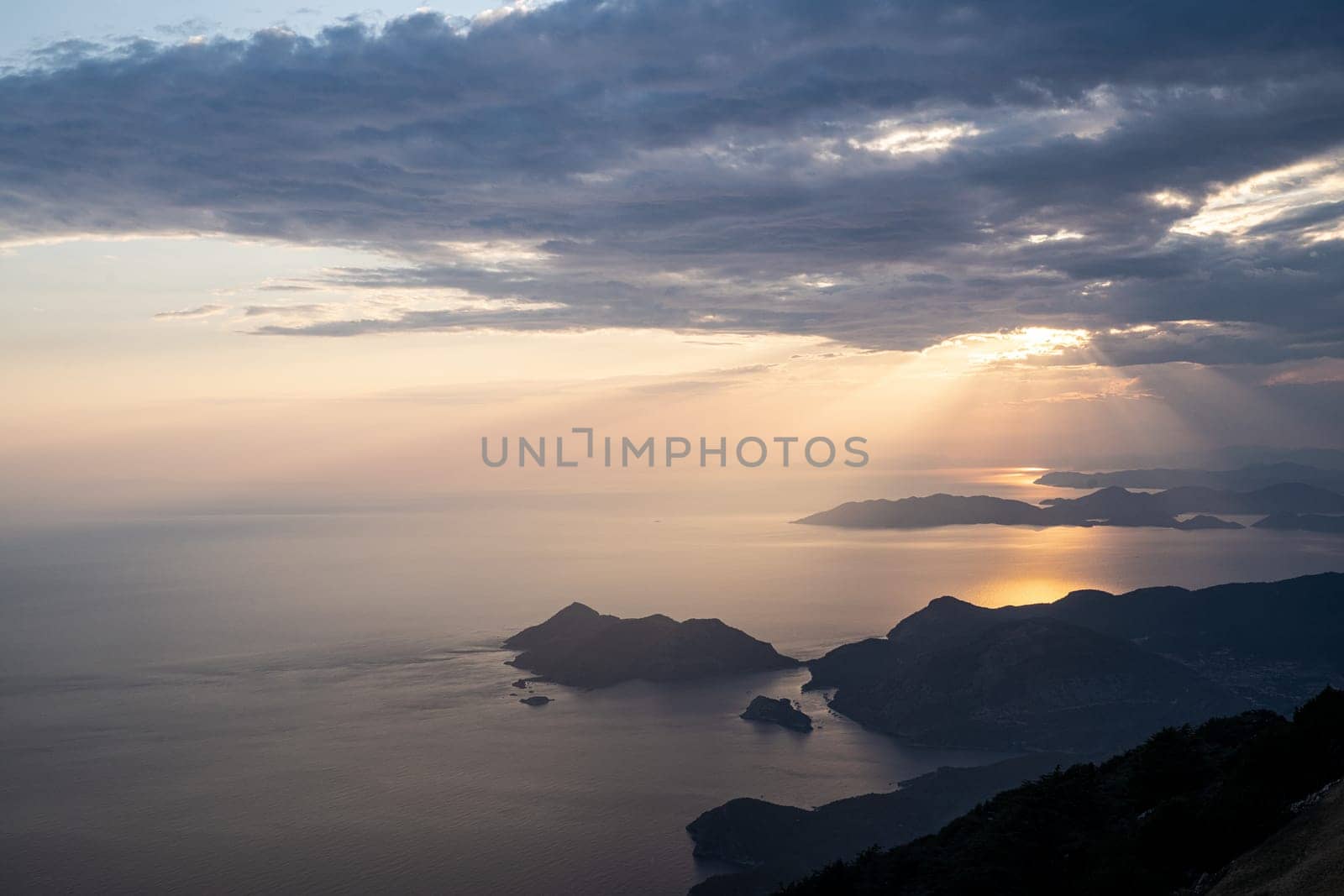beautiful aerial panorama from the Babadag peak of high mountains rising up over the Mediterranean sea at sunset near Oludeniz Blue Lagoon coast in Turkey during summer