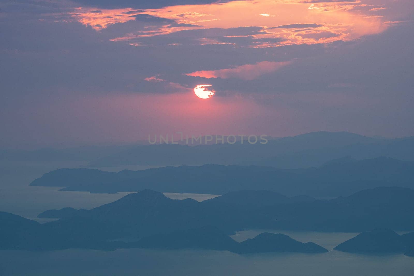 beautiful aerial panorama from the Babadag peak of high mountains rising up over the Mediterranean sea at sunset near Oludeniz Blue Lagoon coast in Turkey during summer