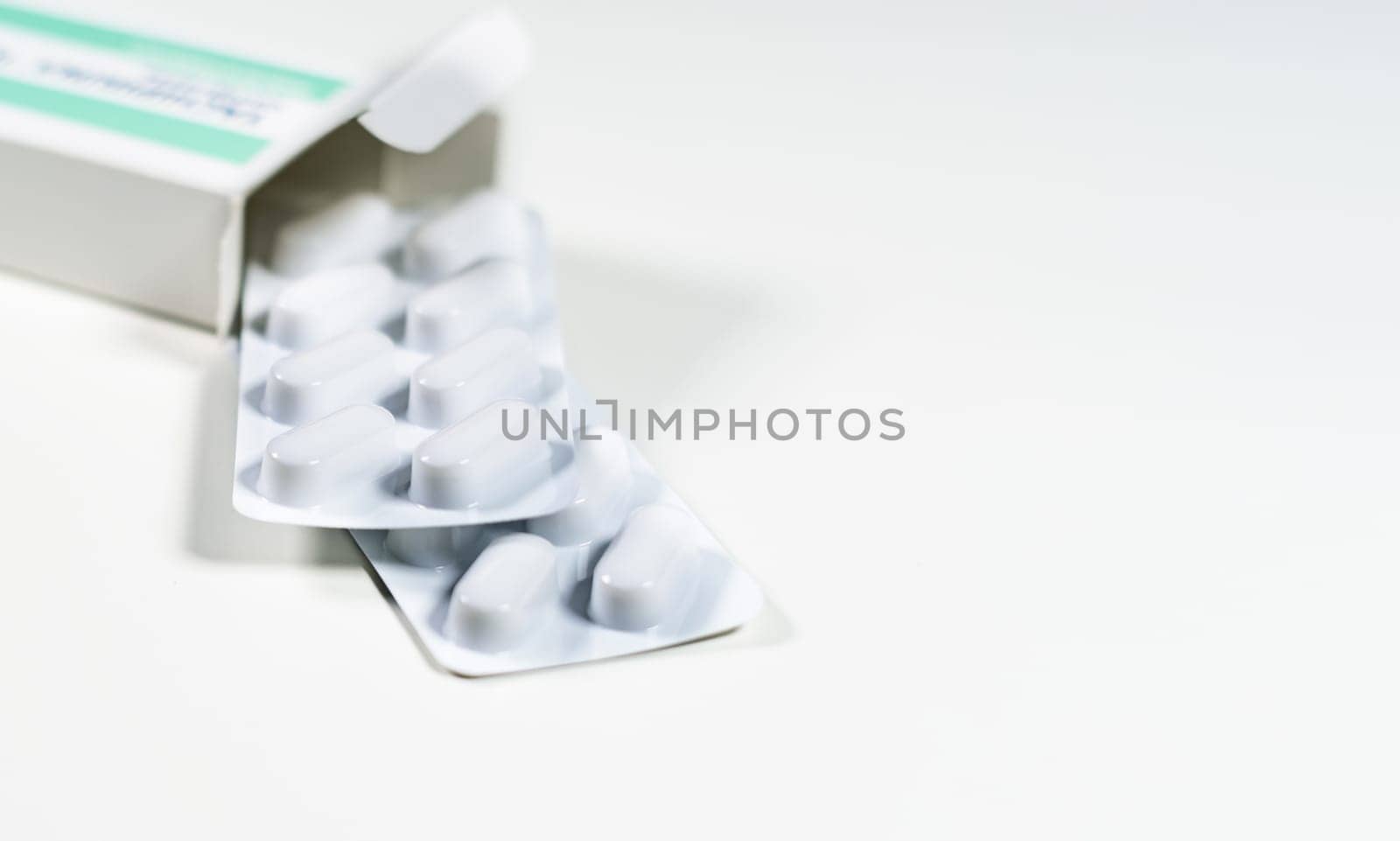 White blister with pills in a green and white box isolated on a white background. Chemistry and medicine. Healthcare and cure concept.
