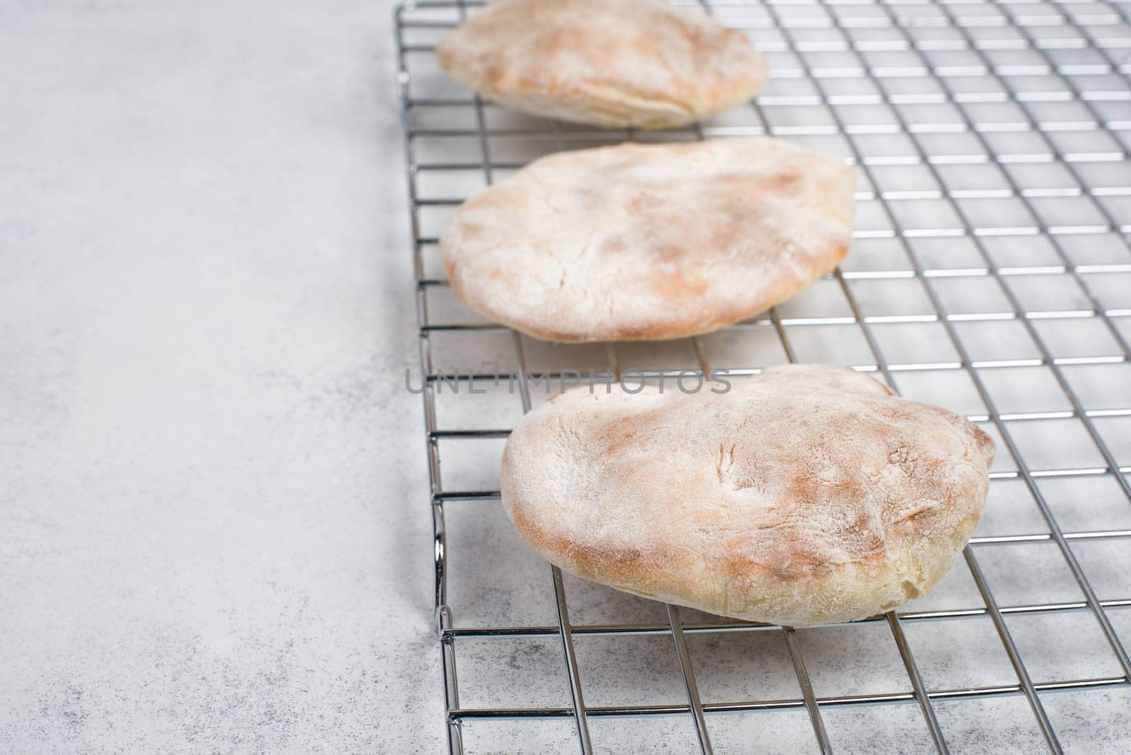 Fresh baked pita bread on a colling grid, empty copy space for text