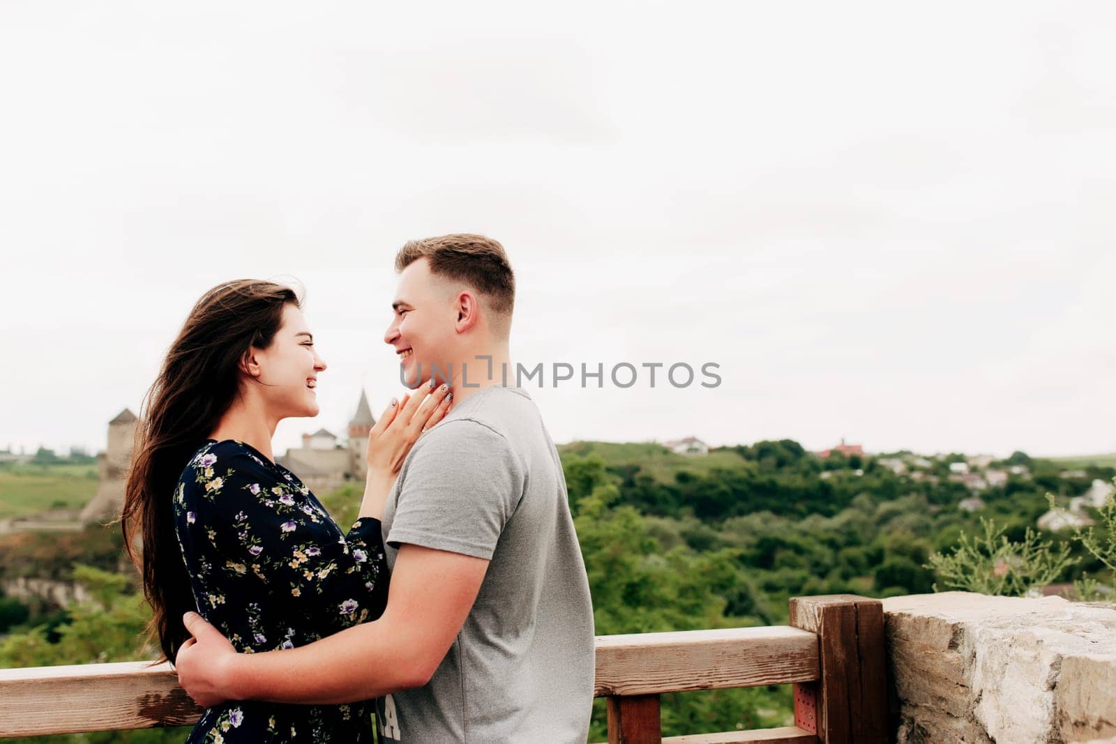 Young Caucasian loving mature couple relaxing during outdoor activities, smiling, hugging and kissing. Walk through route on national park. Two tourists guy and girl joyful walk outside the city