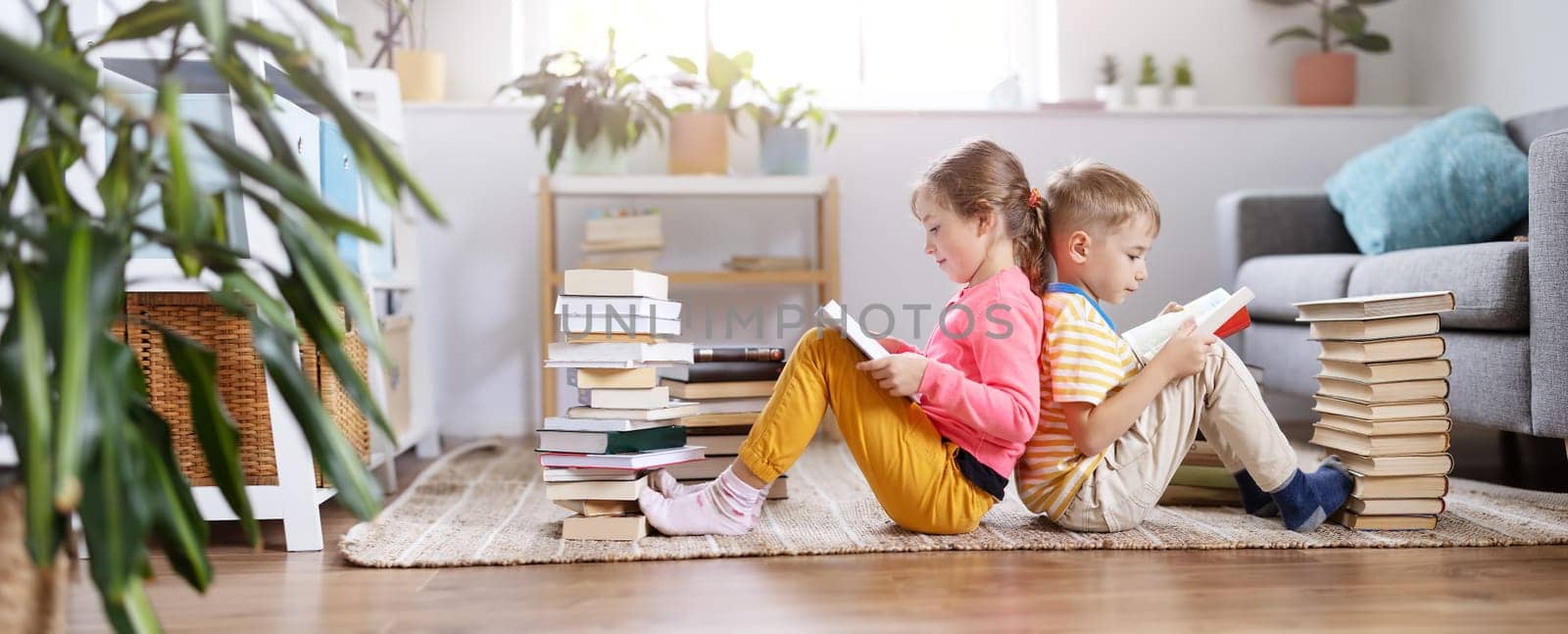 Two children sitting on the floor in the room and reading books- Concept of the family relationship, education and hobby.