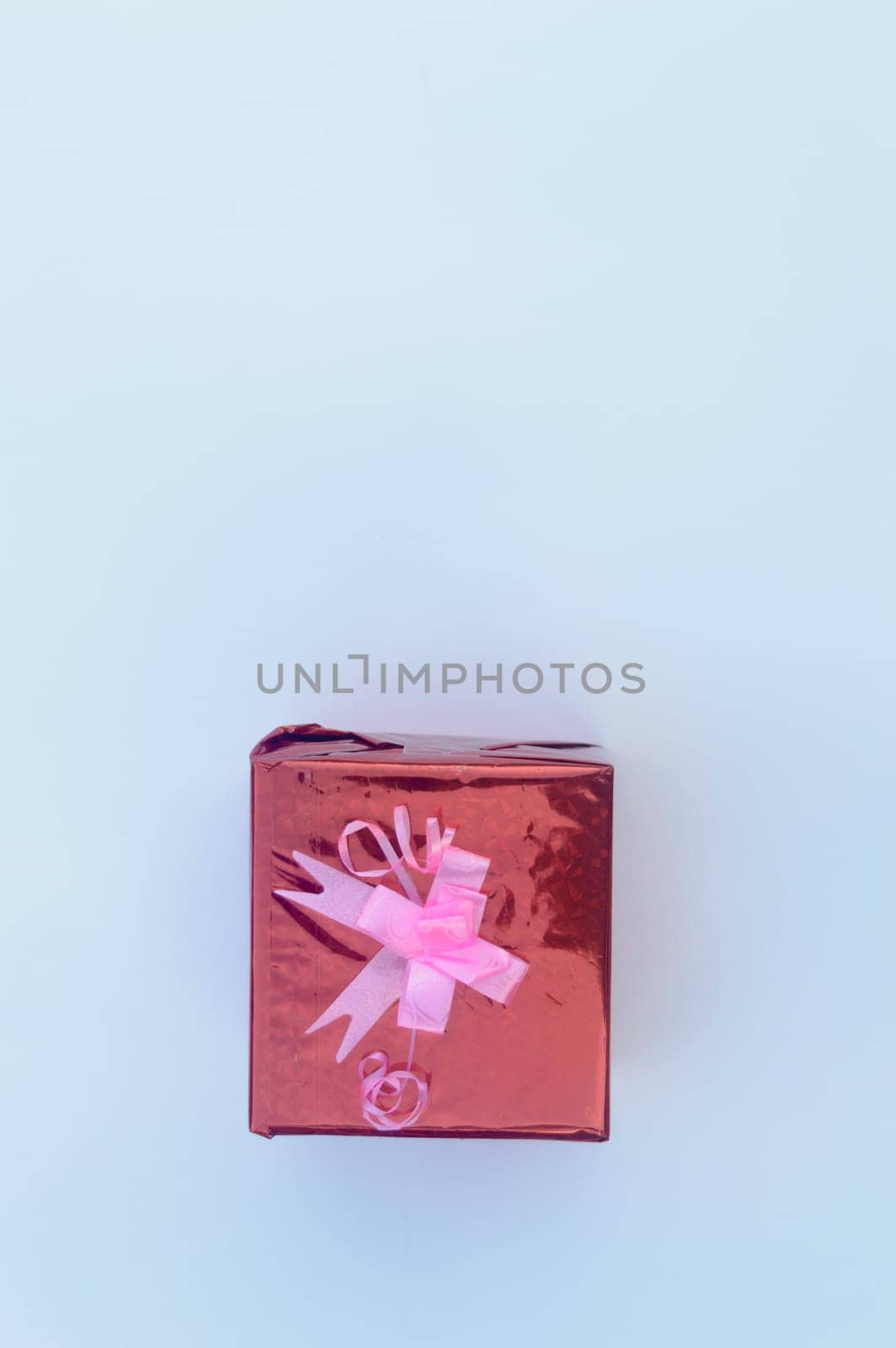 Red Gift box with Ribbon in white background. Table Top View. Flat Lay. Copy Space. Vertical.