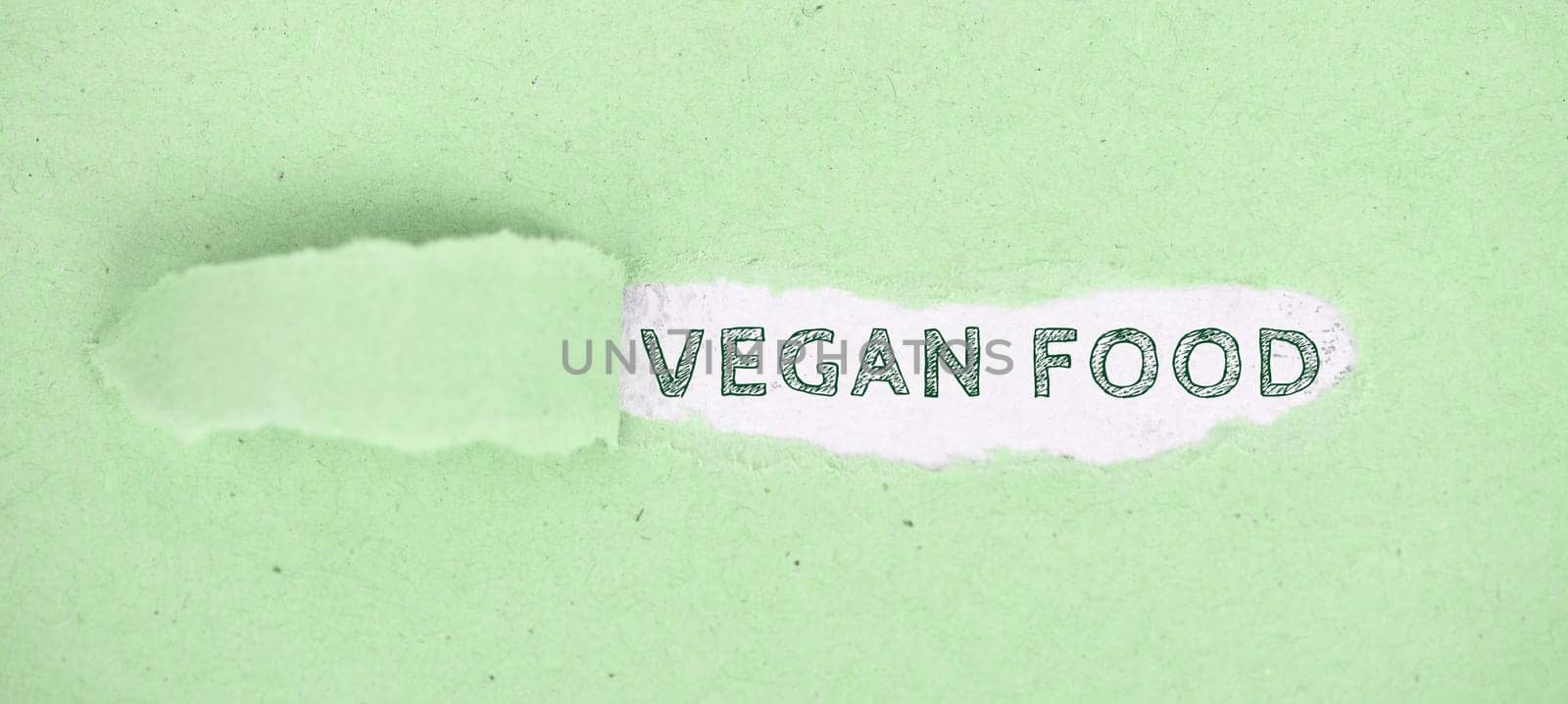 The words vegan food standing on a green ripped up paper