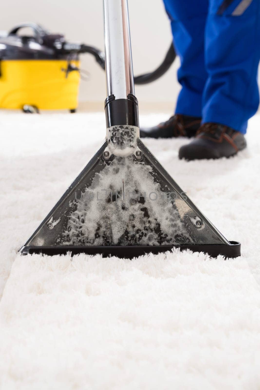 Close-up Of A Janitor Cleaning Carpet With Vacuum Cleaner At Home