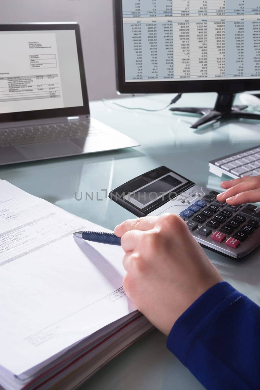 Close-up Of A Businessperson's Hand Calculating Invoice At Workplace
