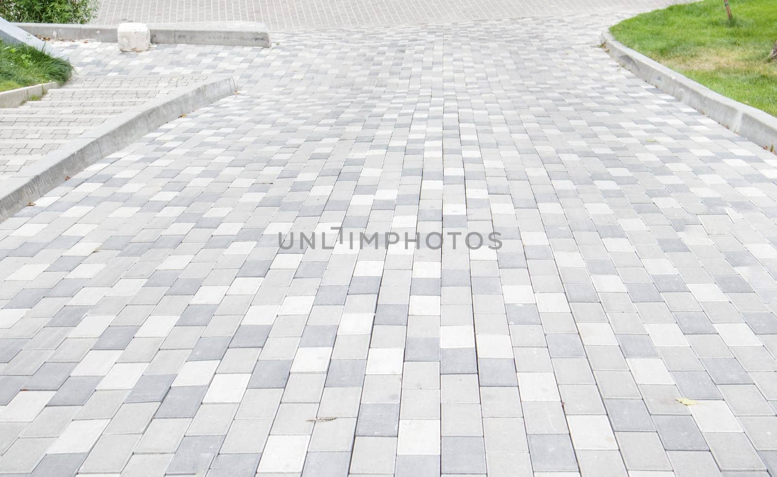 A long descent covered with gray paving slabs. The ramp is paved with concrete tiles. Wheelchair and bicycle accessibility concept