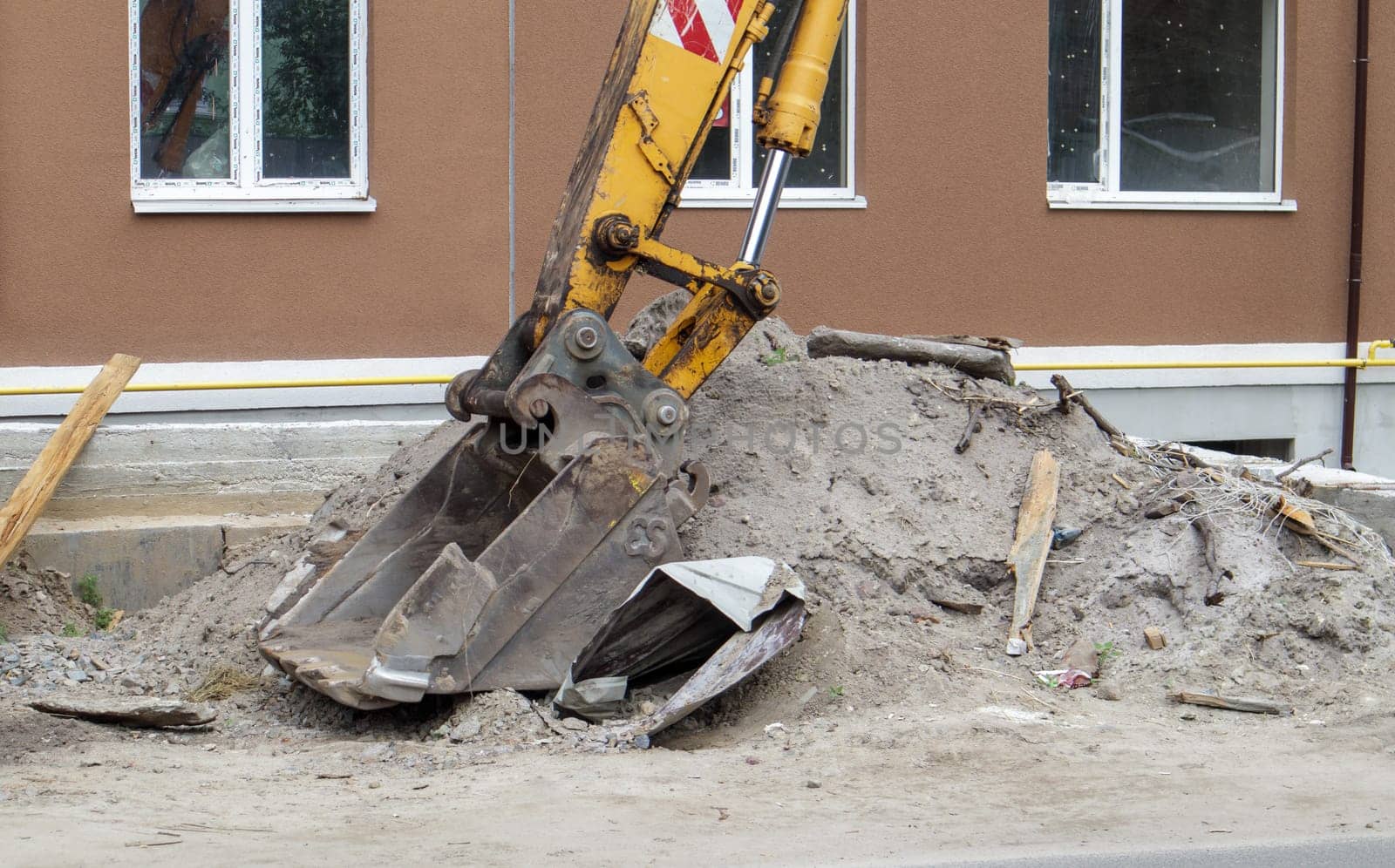 Mobile crane loader of yellow color on the background of a building under construction. German-Swiss international equipment manufacturer. The excavator is used for earthworks