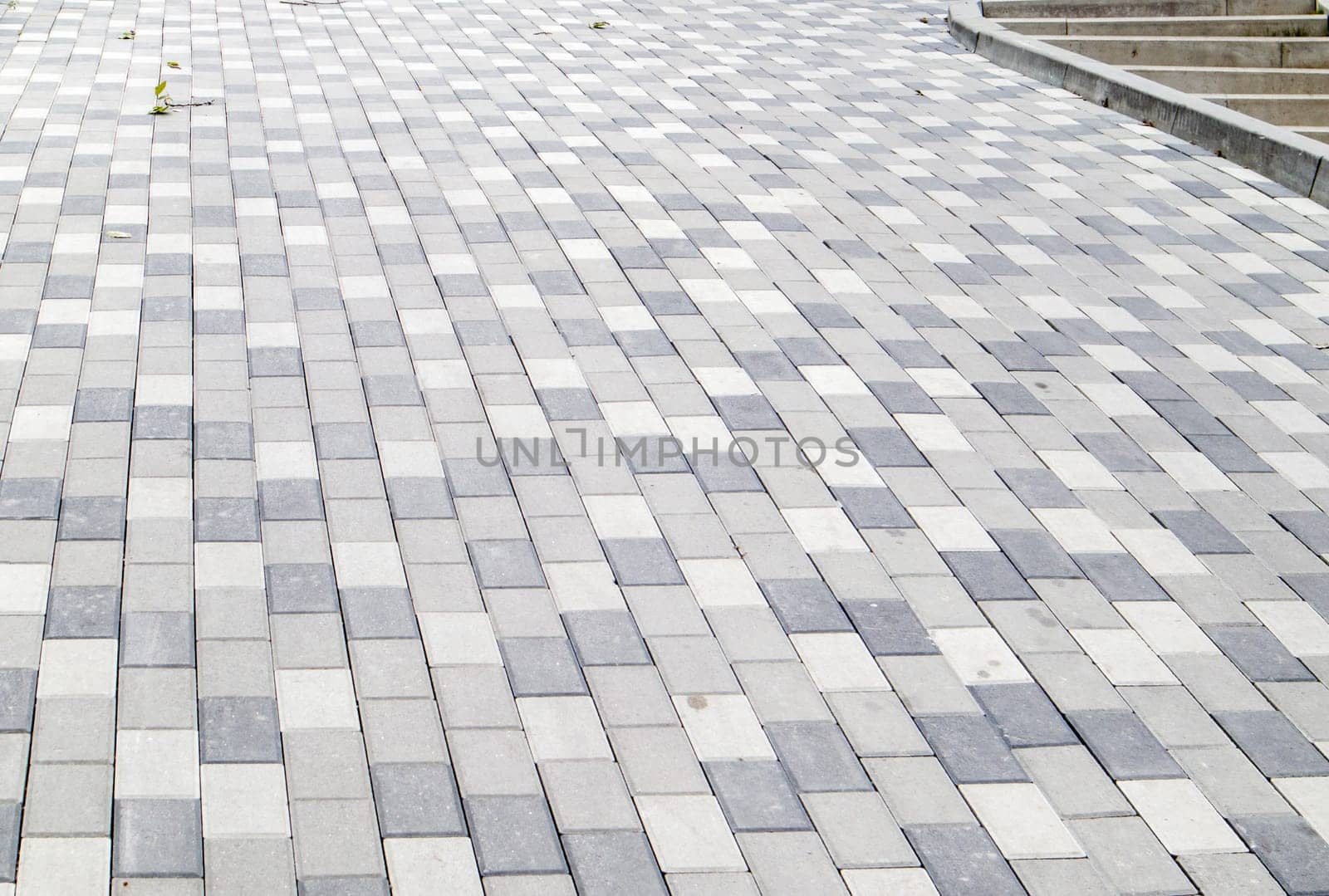 A long descent covered with gray paving slabs. The ramp is paved with concrete tiles. Wheelchair and bicycle accessibility concept