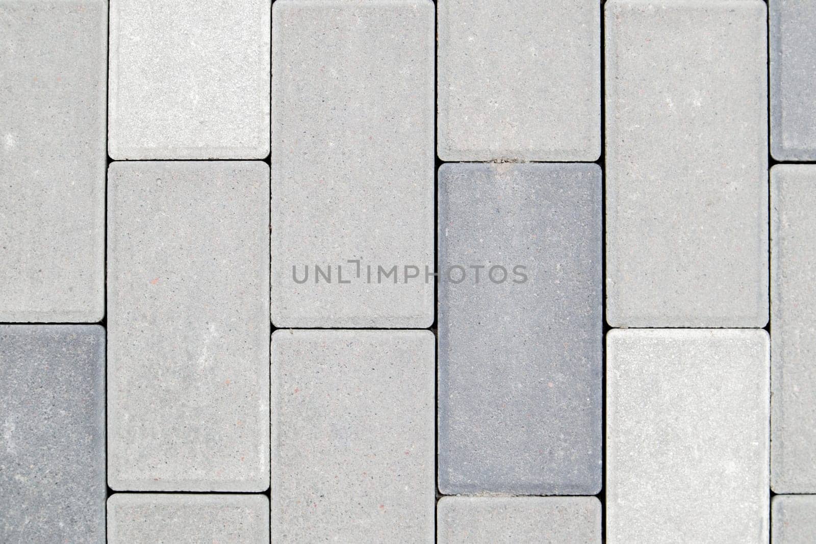 Concrete or paved newly laid gray paving slabs or stones for floors or walkways. Concrete paving slabs in the backyard or road paving. Garden brick path in the courtyard on a sandy foundation
