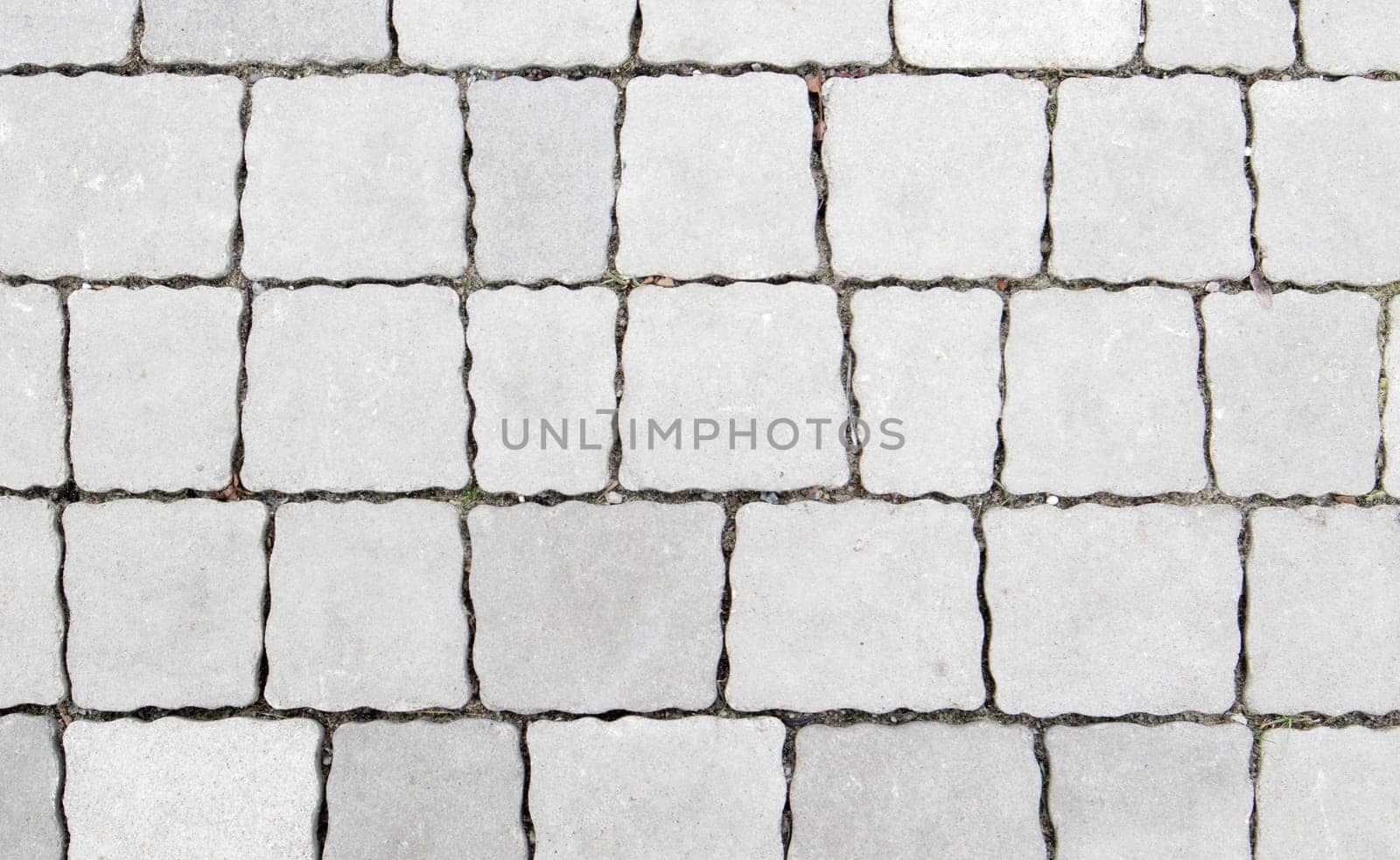 Concrete or paved newly laid gray paving slabs or stones for floors or walkways. Concrete paving slabs in the backyard or road paving. Garden brick path in the courtyard on a sandy foundation