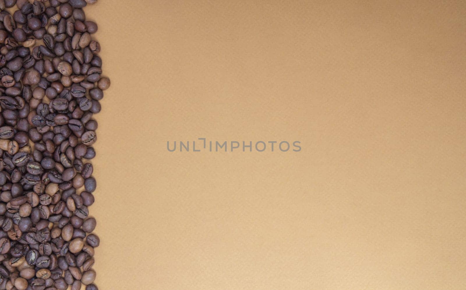 Fresh roasted coffee beans on a soft coffee or brown background. Selective focus. Copy space. View from above