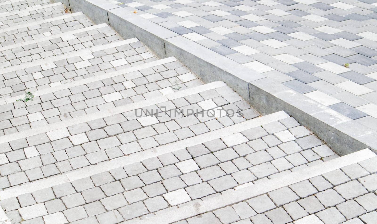 Steps from paving slabs and curbs. Rows of gray steps made of gray paving slabs are laid out evenly, consistently and tightly to each other. Paving stone steps slab gray background
