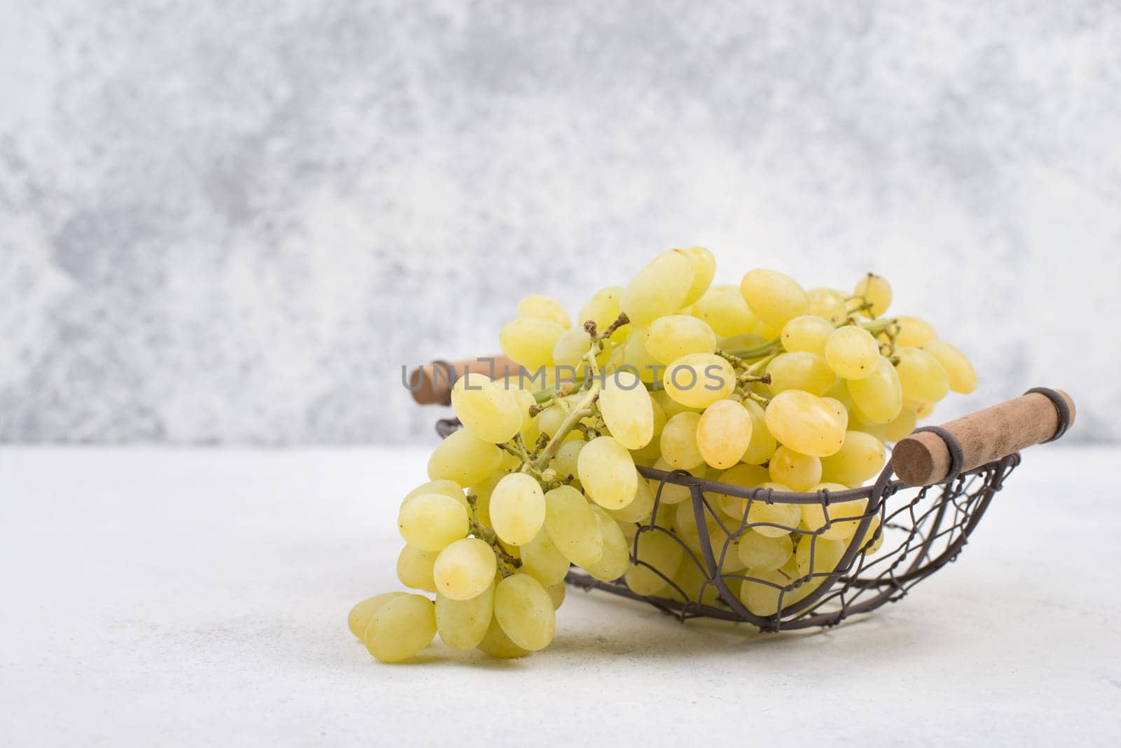 Grapes in a basket on a textured background, empty space for text