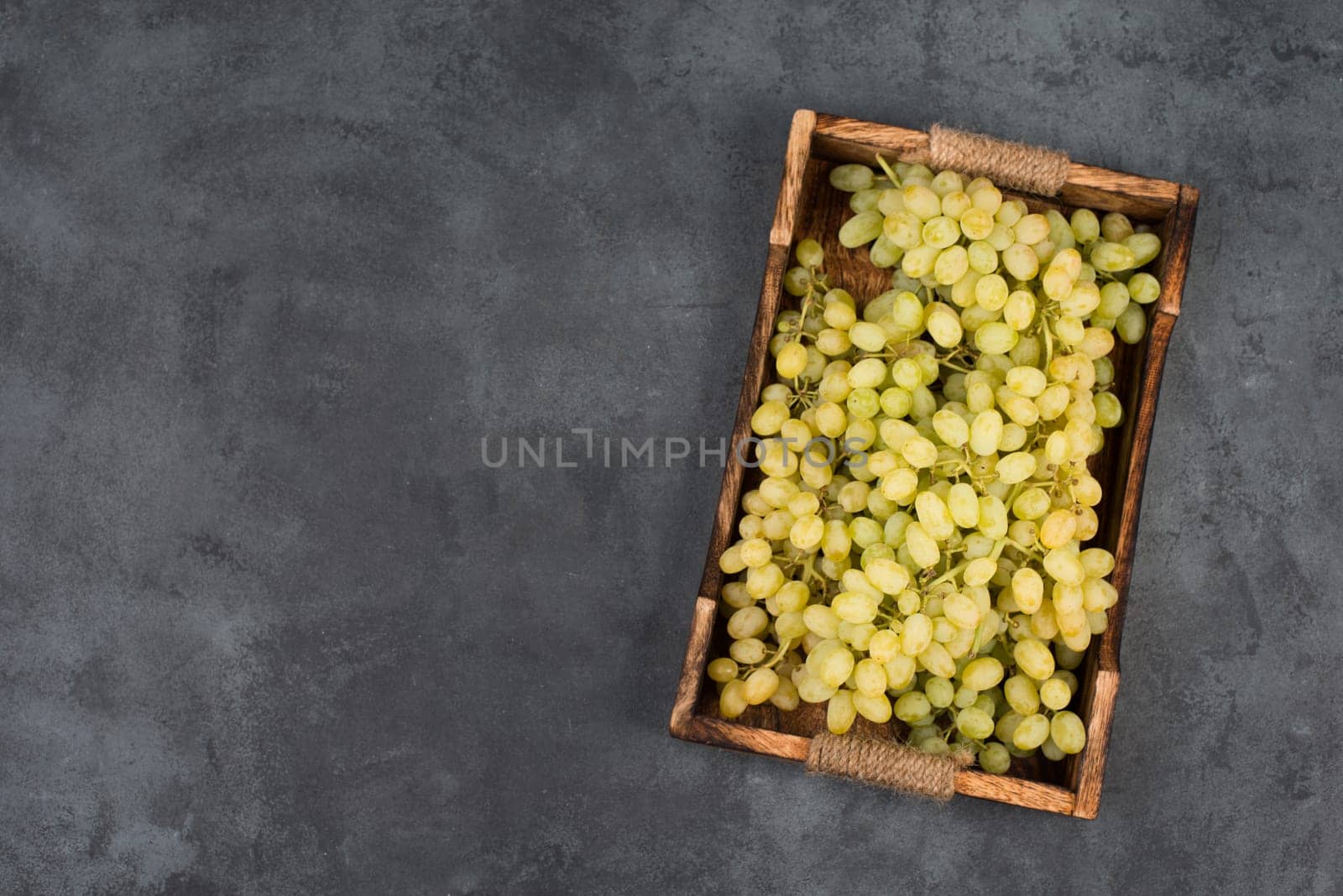 Grapes in a basket on a textured background, empty space for text
