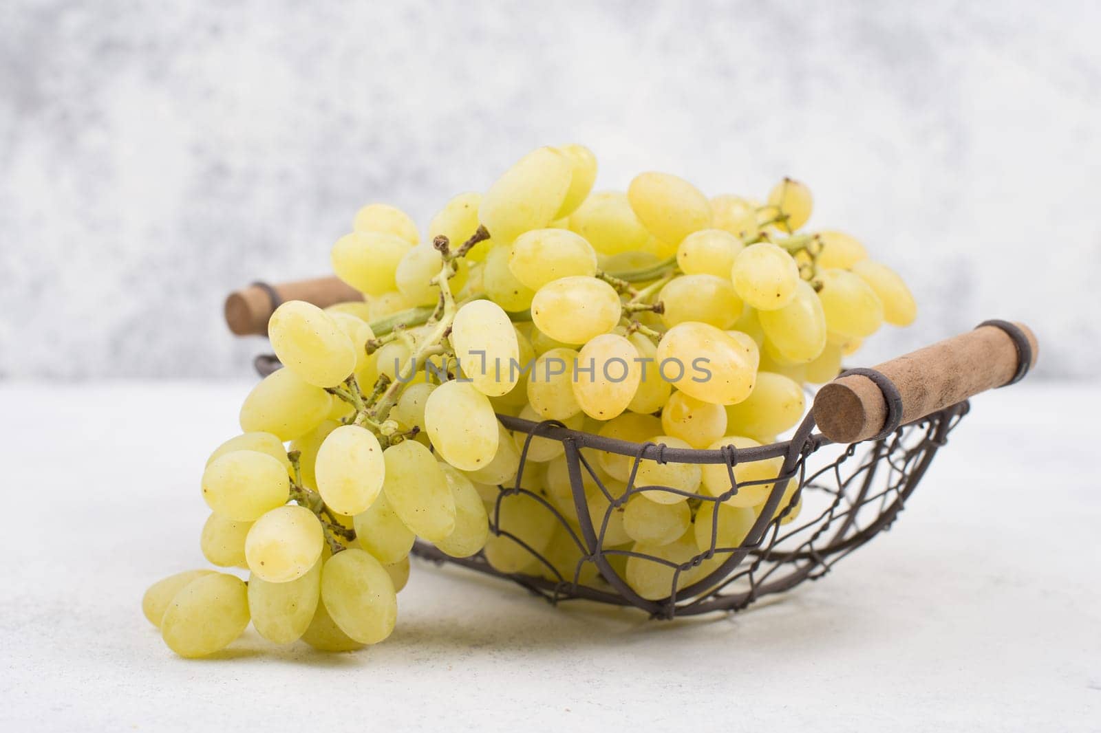 Grapes in a basket on a textured background, empty space for text