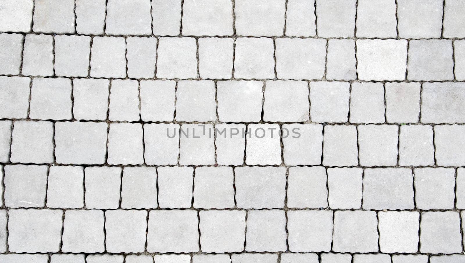 Concrete or paved newly laid gray paving slabs or stones for floors or walkways. Concrete paving slabs in the backyard or road paving. Garden brick path in the courtyard on a sandy foundation