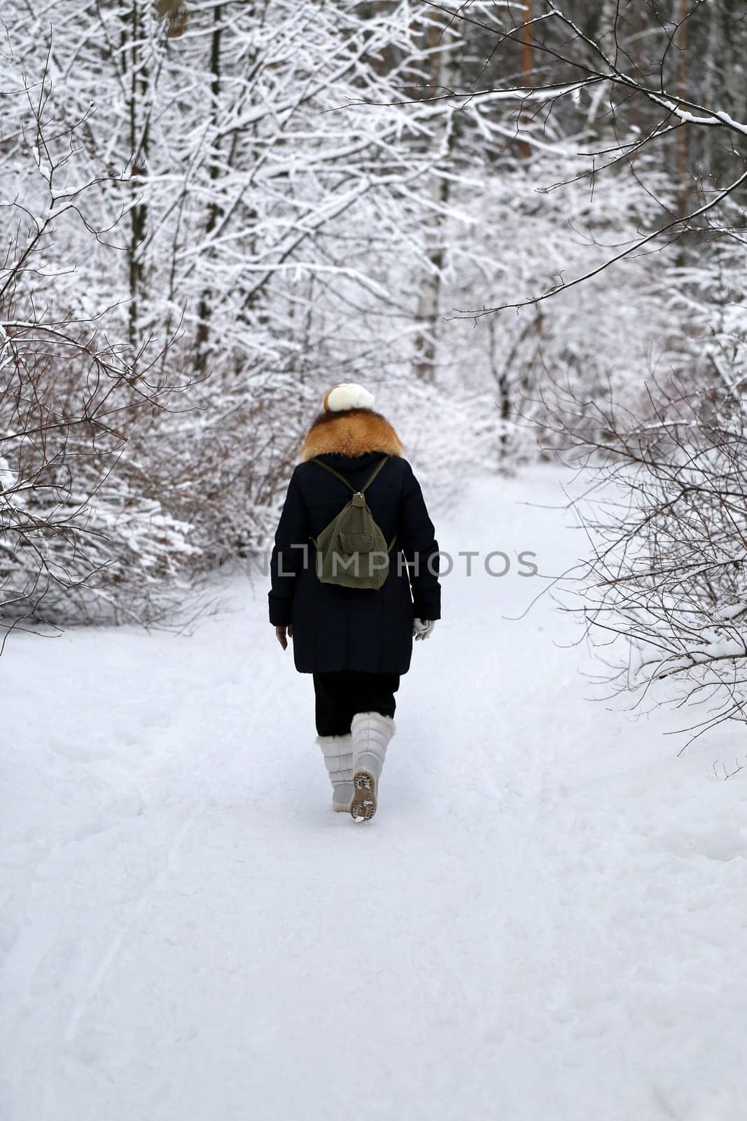 woman walks down a snowy path in winter forest