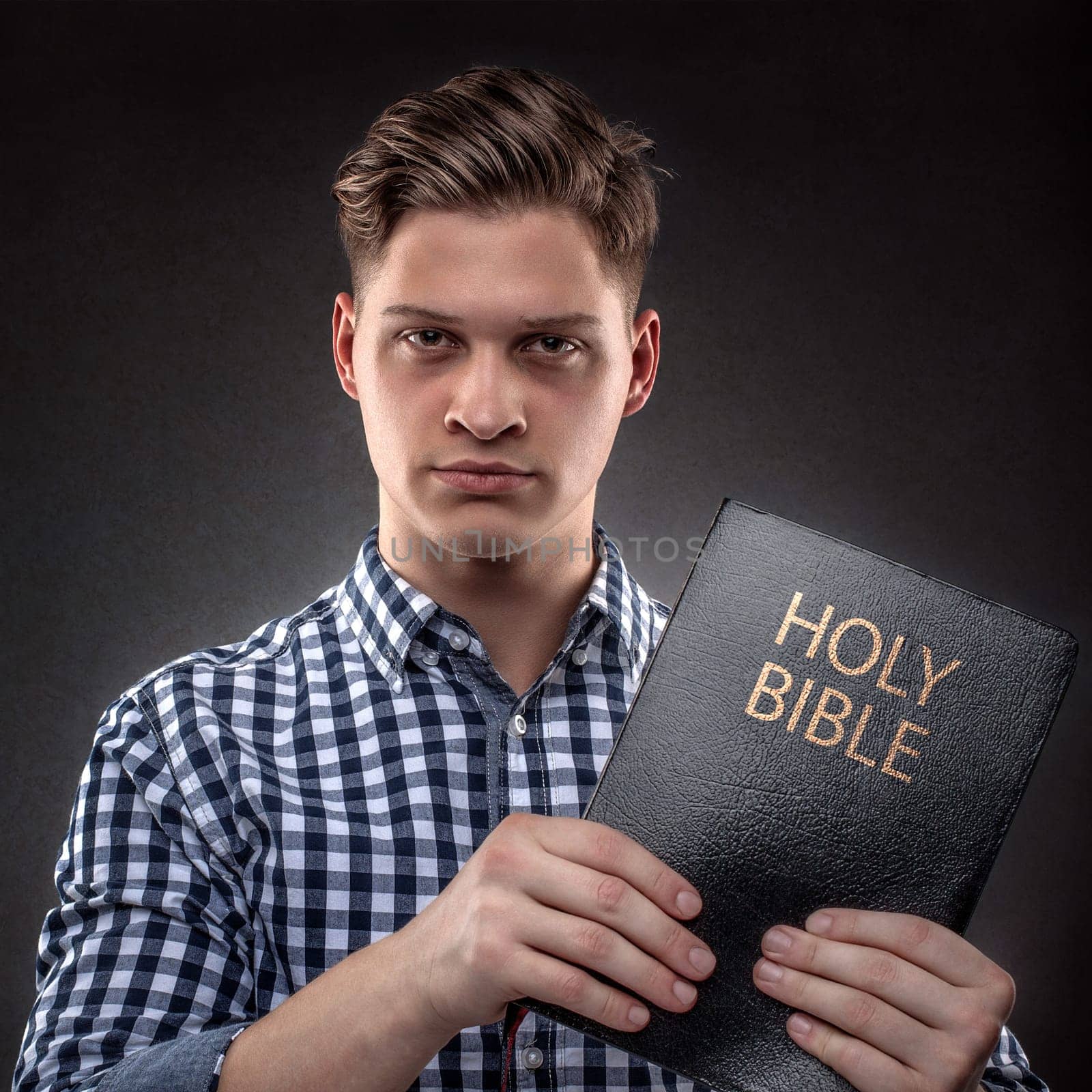 Young christian man showing showing with determination a Holy Bible  (concept against temptation by God's Word)