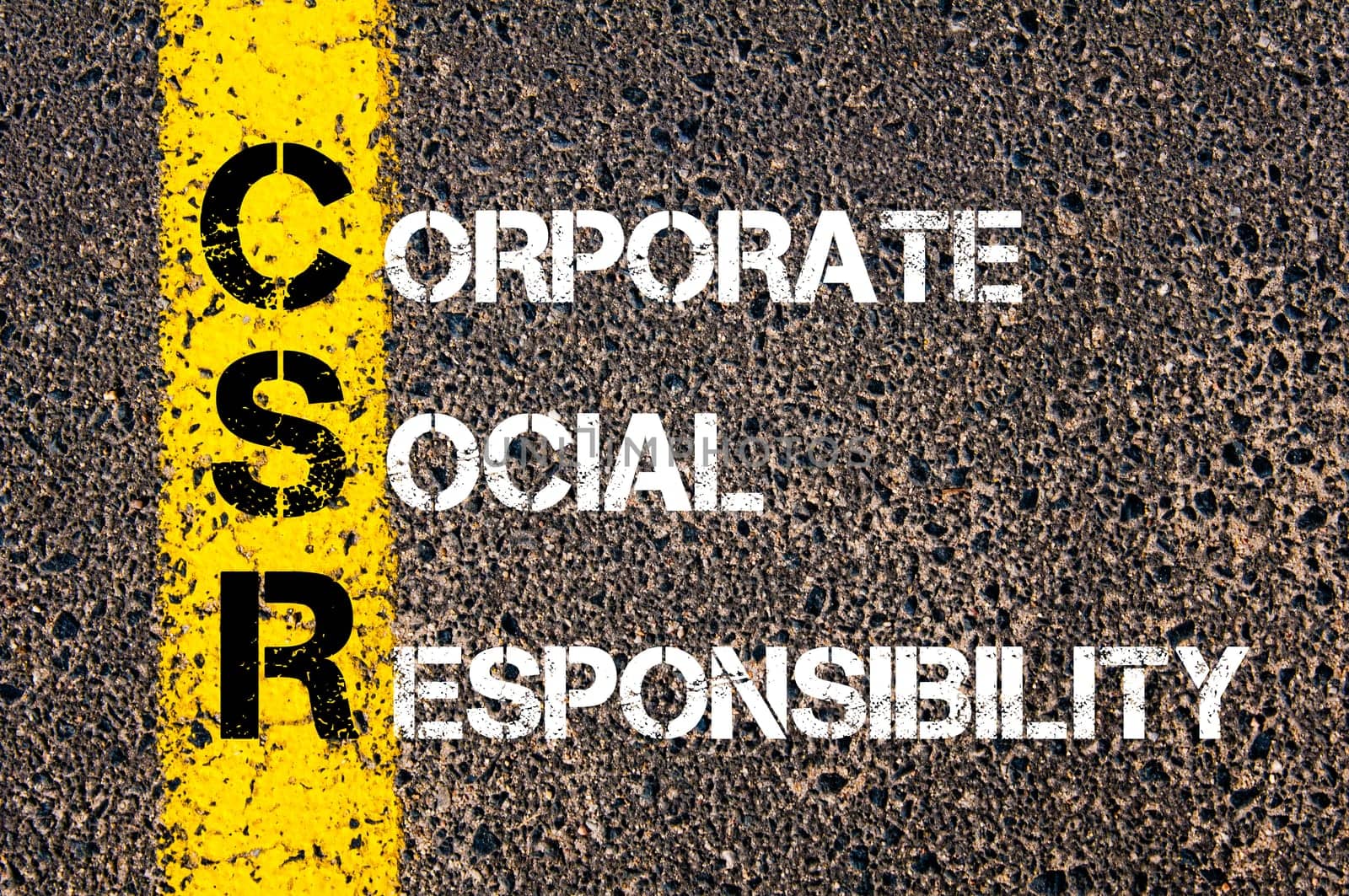 Acronym CSR - Corporate Social Responsibility.Business Conceptual image with yellow paint line on the road over asphalt stone background...