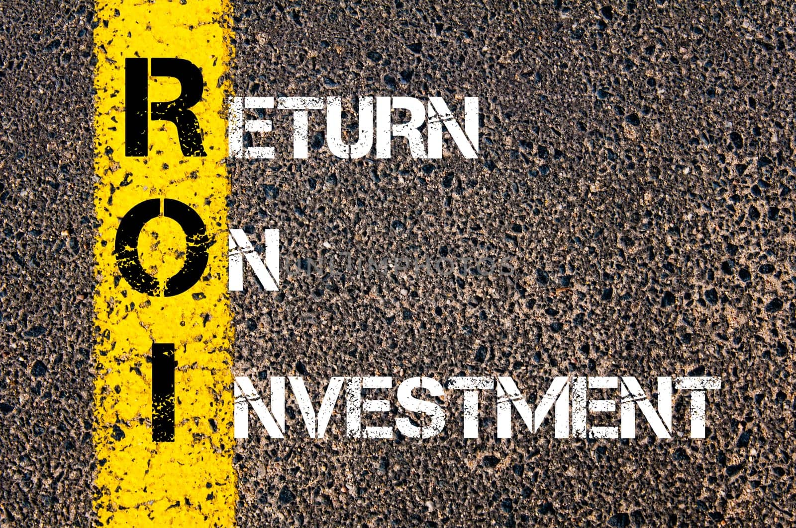 Acronym ROI - Return On Investment. Business Conceptual image with yellow paint line on the road over asphalt stone background.