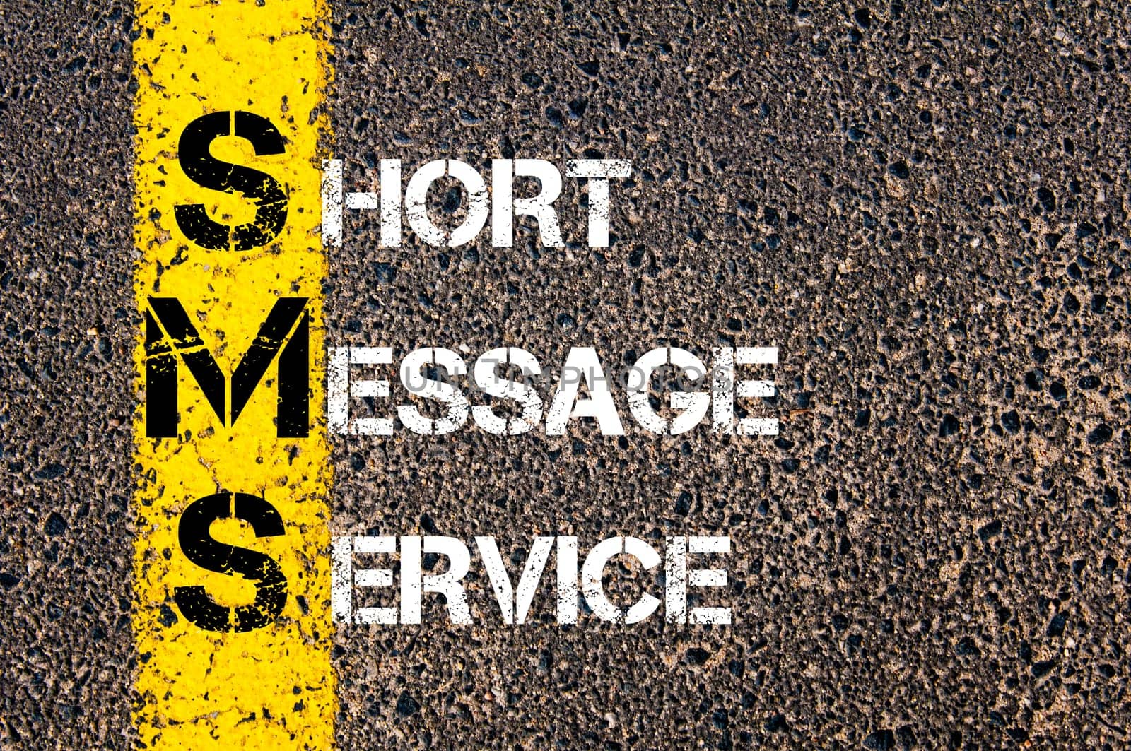 Acronym SMS - Short Message Service. Business Conceptual image with yellow paint line on the road over asphalt stone background.