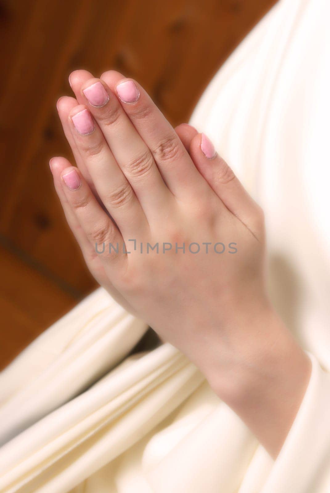 A young woman brings her hands together in prayer to the almighty father in heaven.