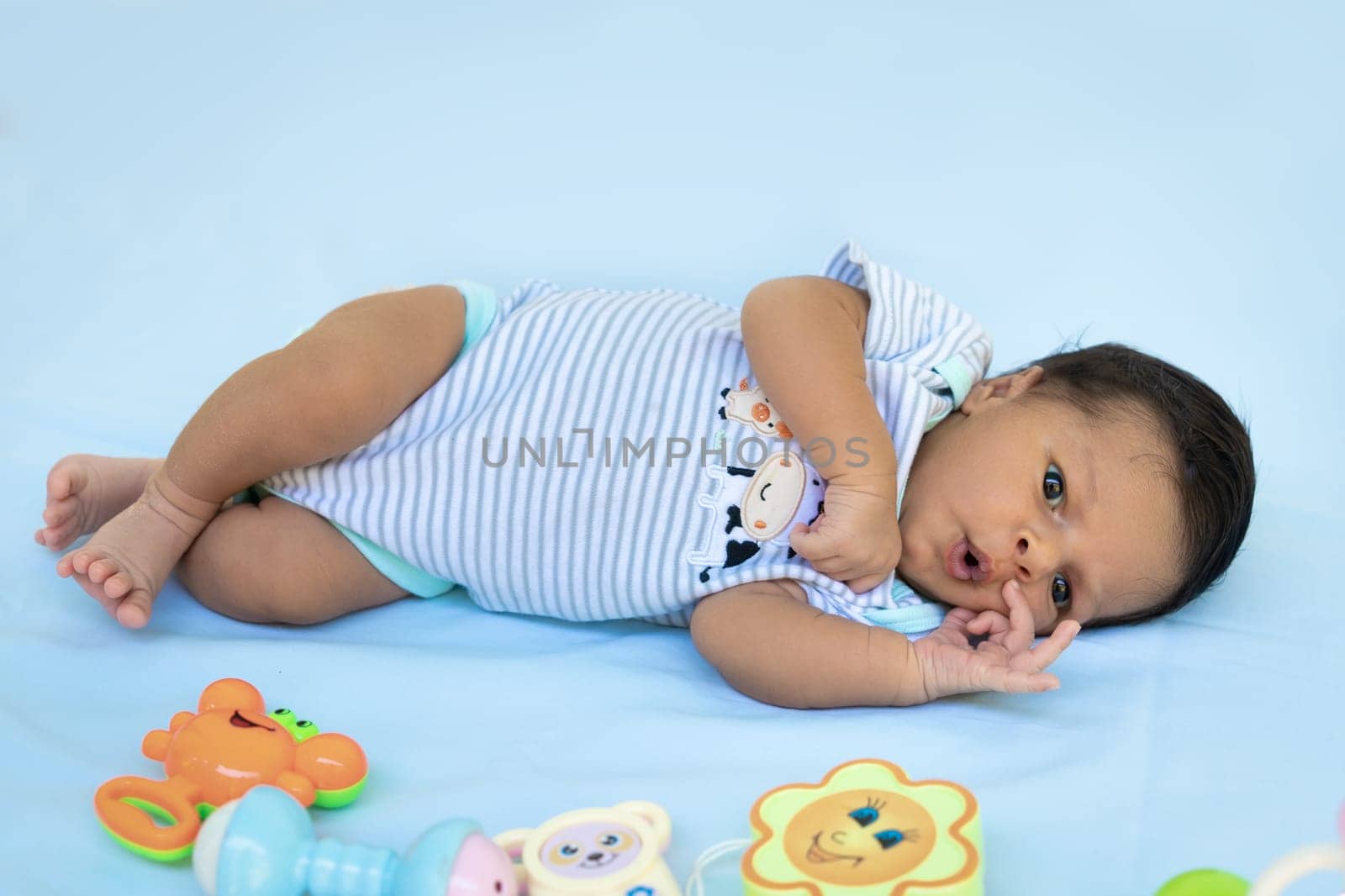 Full-length picture of an infant with his eyes open lying on a blue cloth