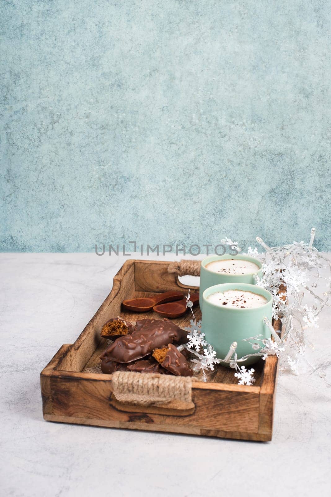 Coffee cups and chocolate coated gingerbread in a wooden basket, empty copy space, christmas season