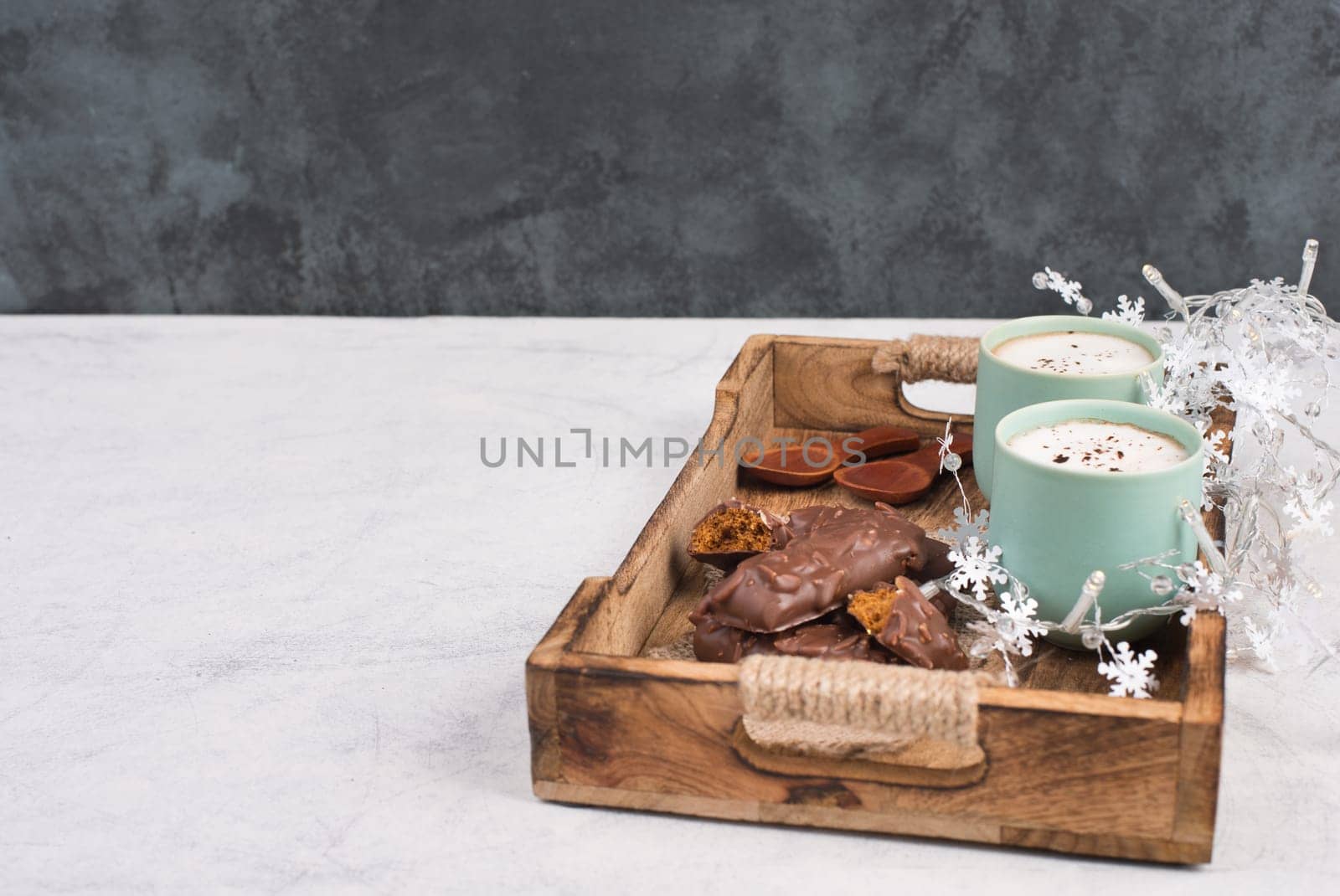 Coffee cups and chocolate coated gingerbread in a wooden basket, empty copy space, christmas season