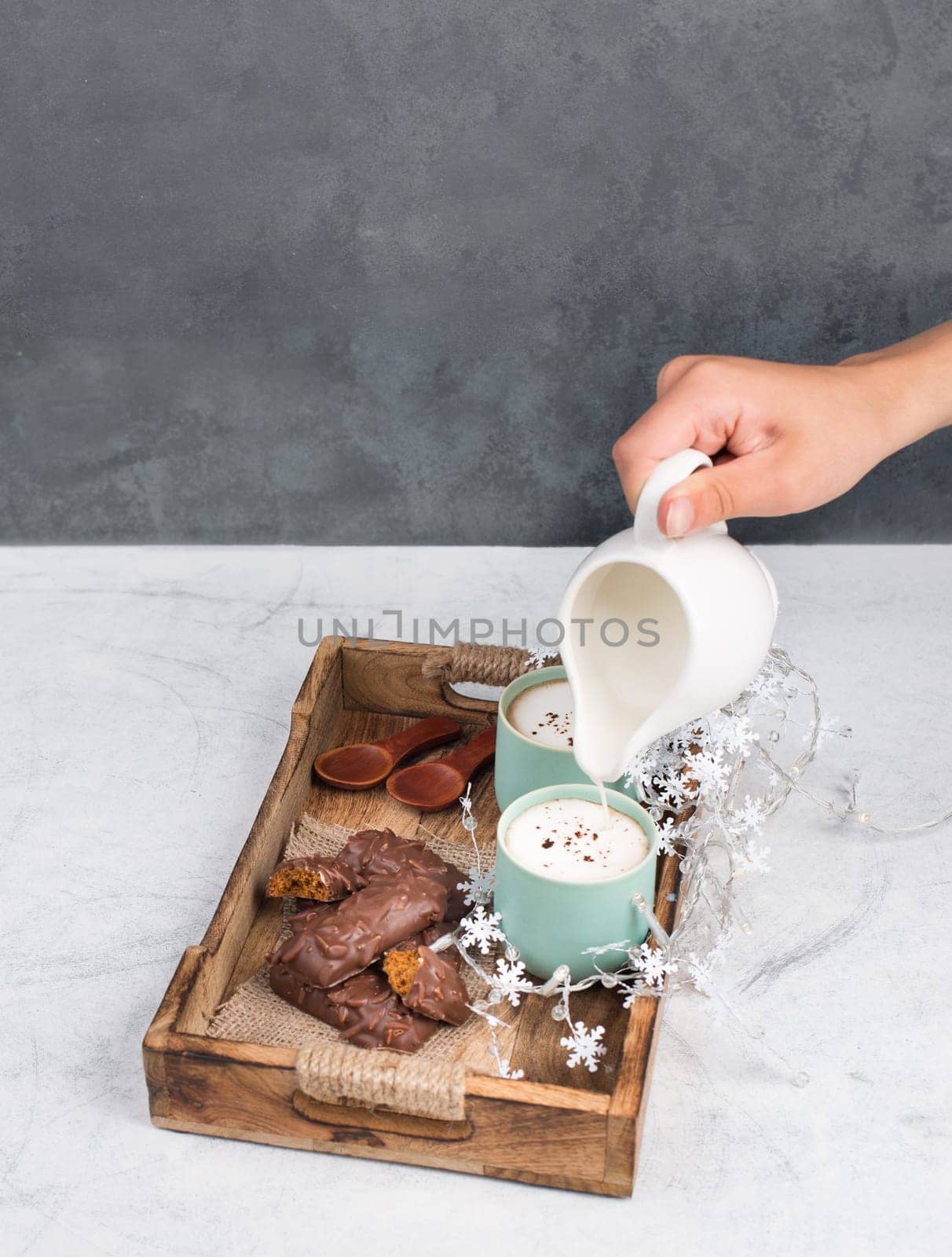 Coffee cups and chocolate coated gingerbread in a wooden basket, empty copy space, christmas season